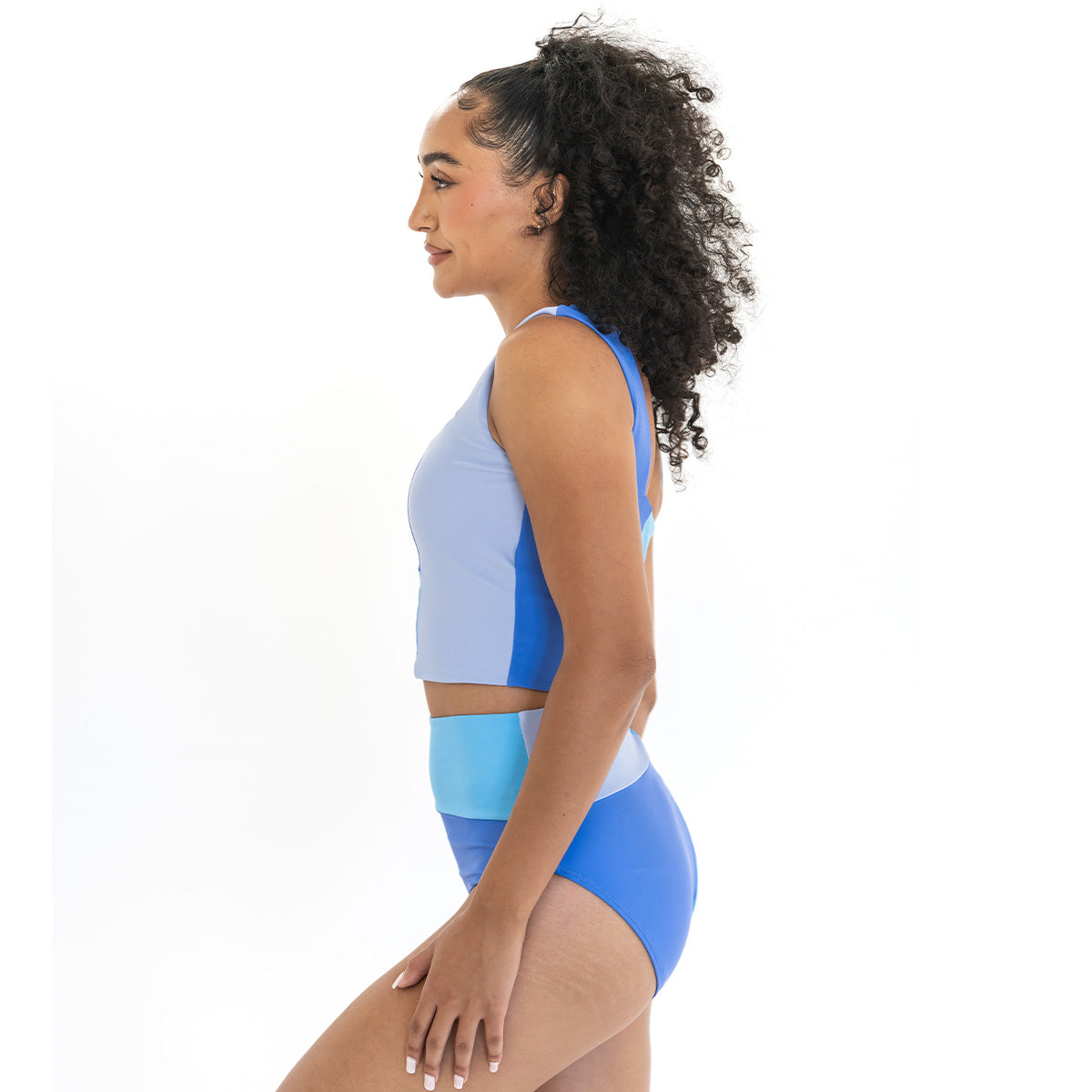 Woman wearing a blue and gray sports bra and shorts set on a white background