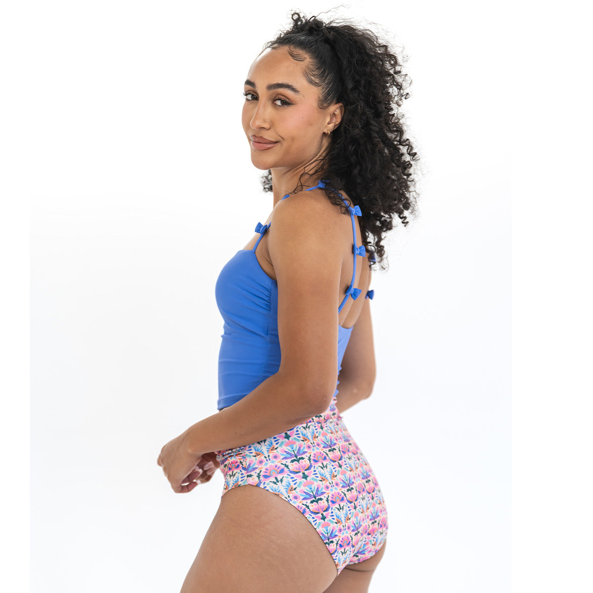 Woman wearing a blue top and floral shorts on a white background