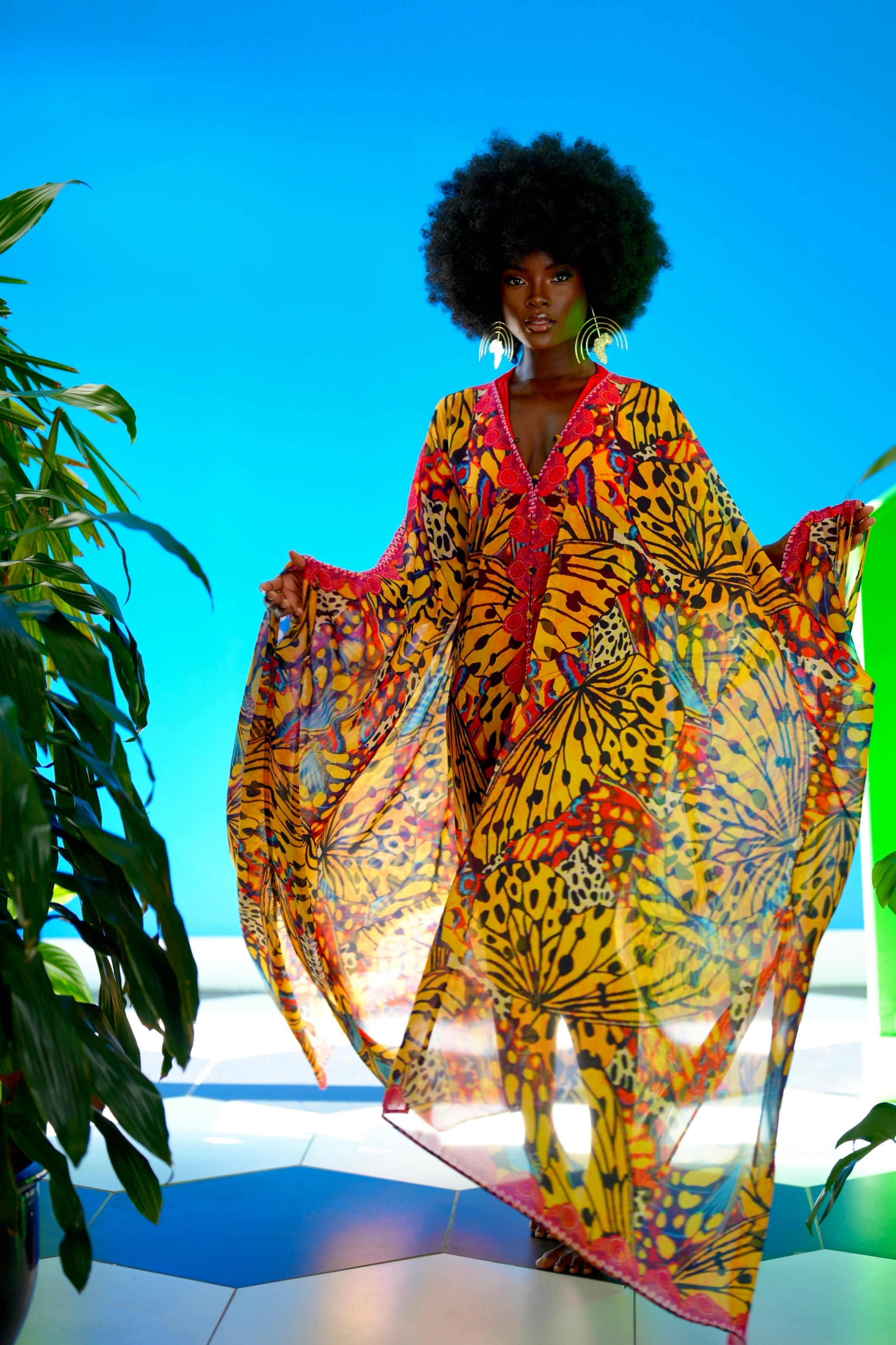 Woman wearing a colorful patterned dress against a blue sky.
