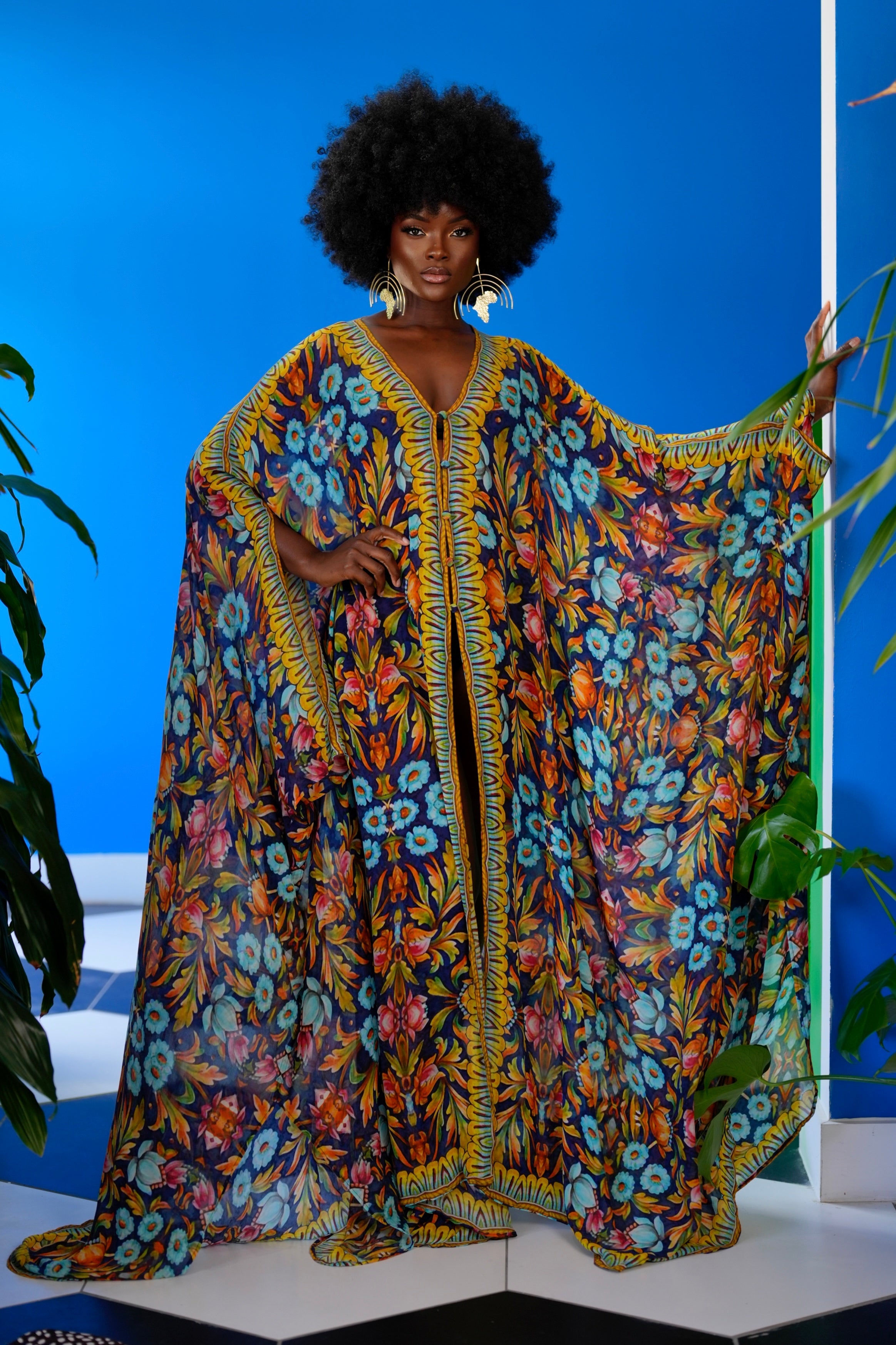 Woman wearing a colorful floral caftan against a blue background