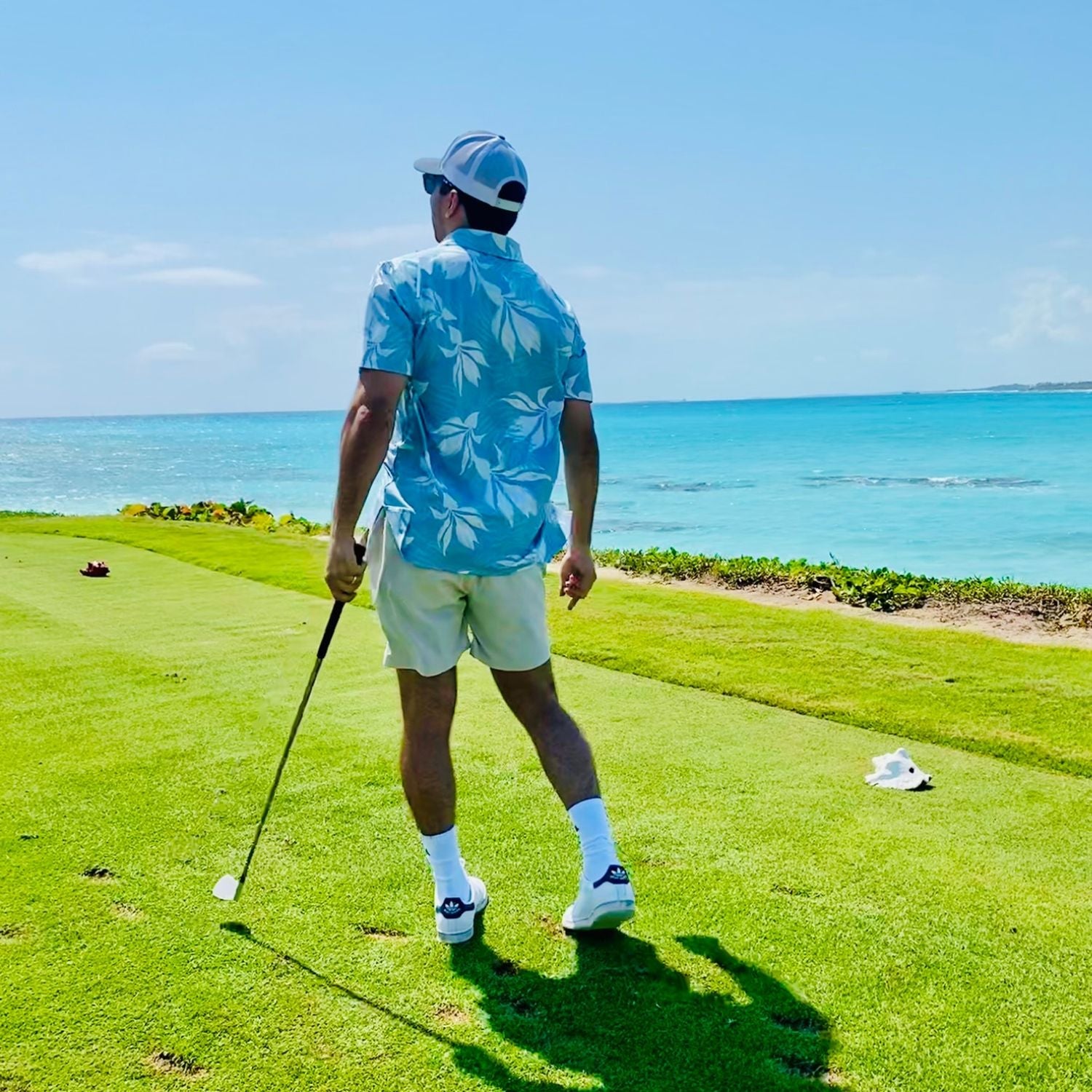 Man playing golf on a green course with ocean view