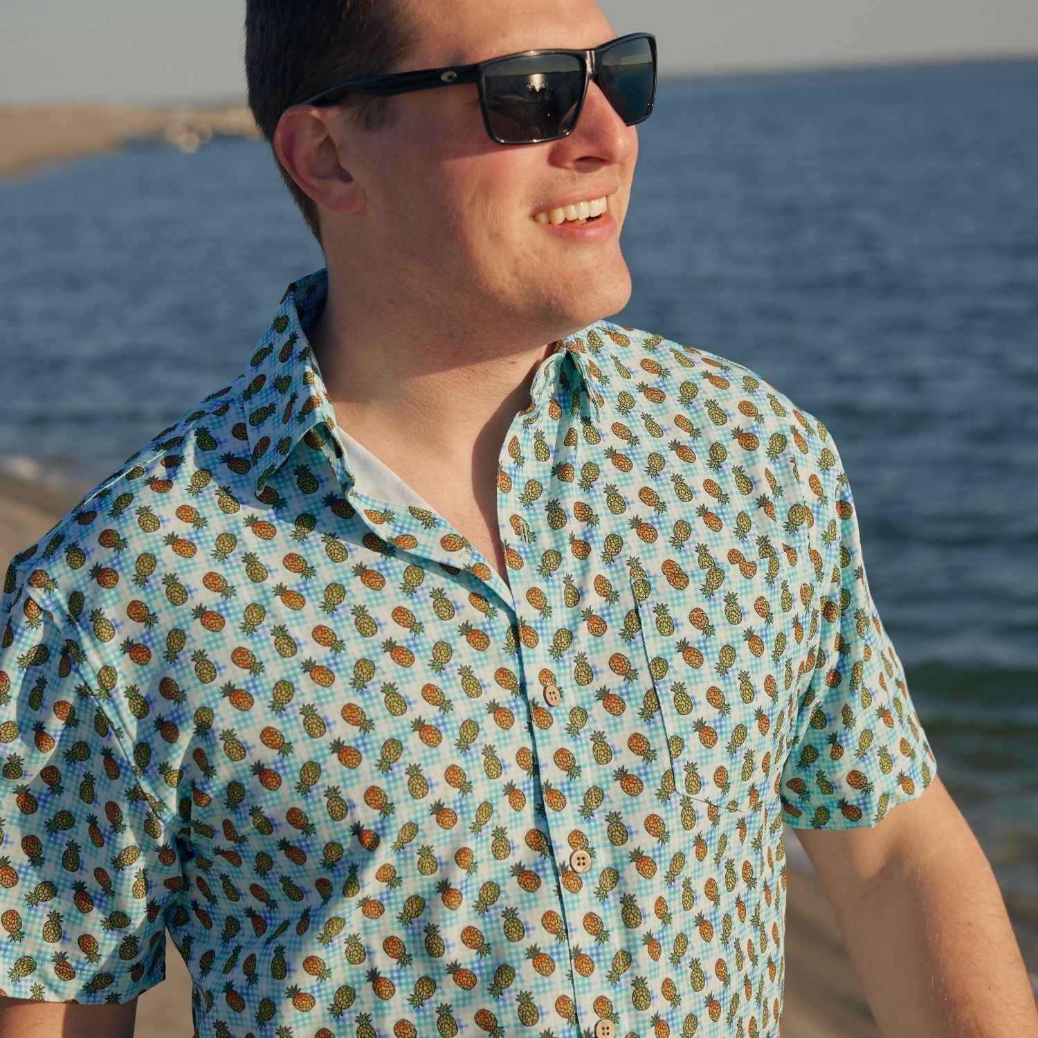 Man wearing a patterned shirt and sunglasses by the water