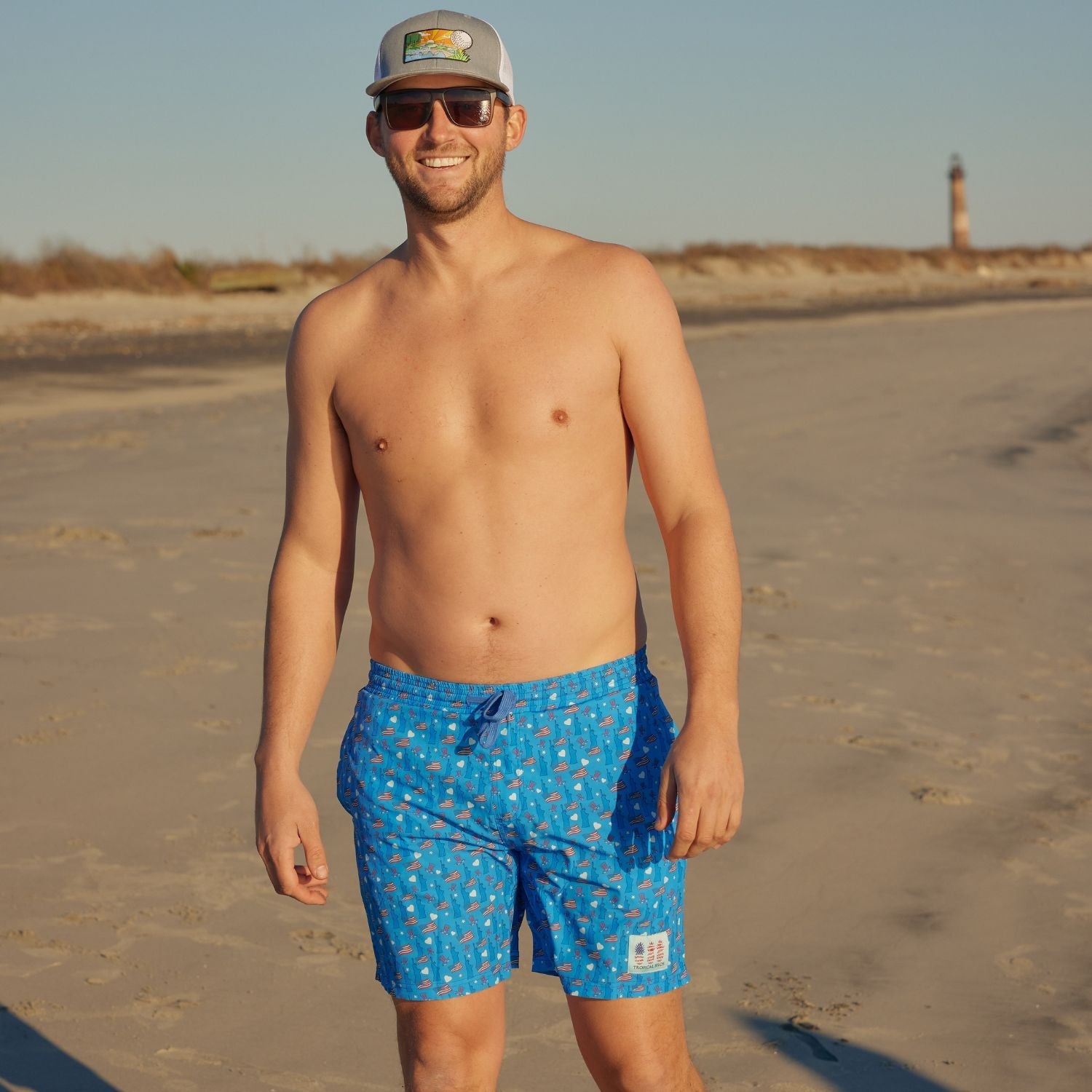 Man wearing blue swim shorts with a pattern on a beach