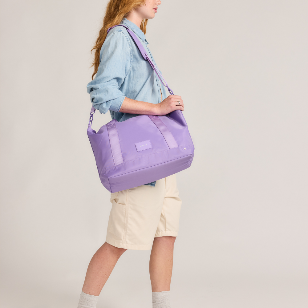 Person holding a purple bag against a plain background