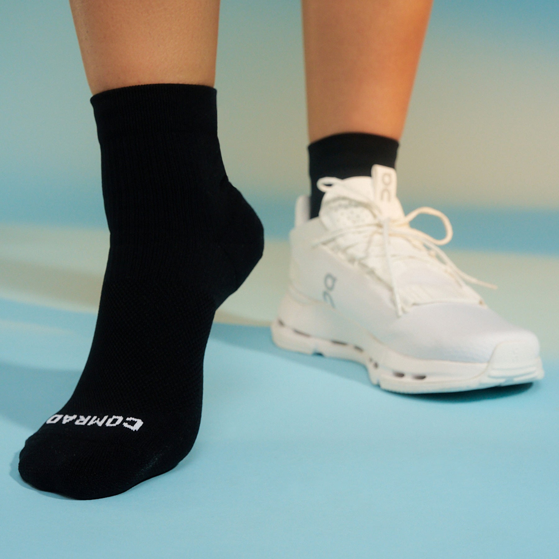 Black socks with white text and white sneakers on a light blue background