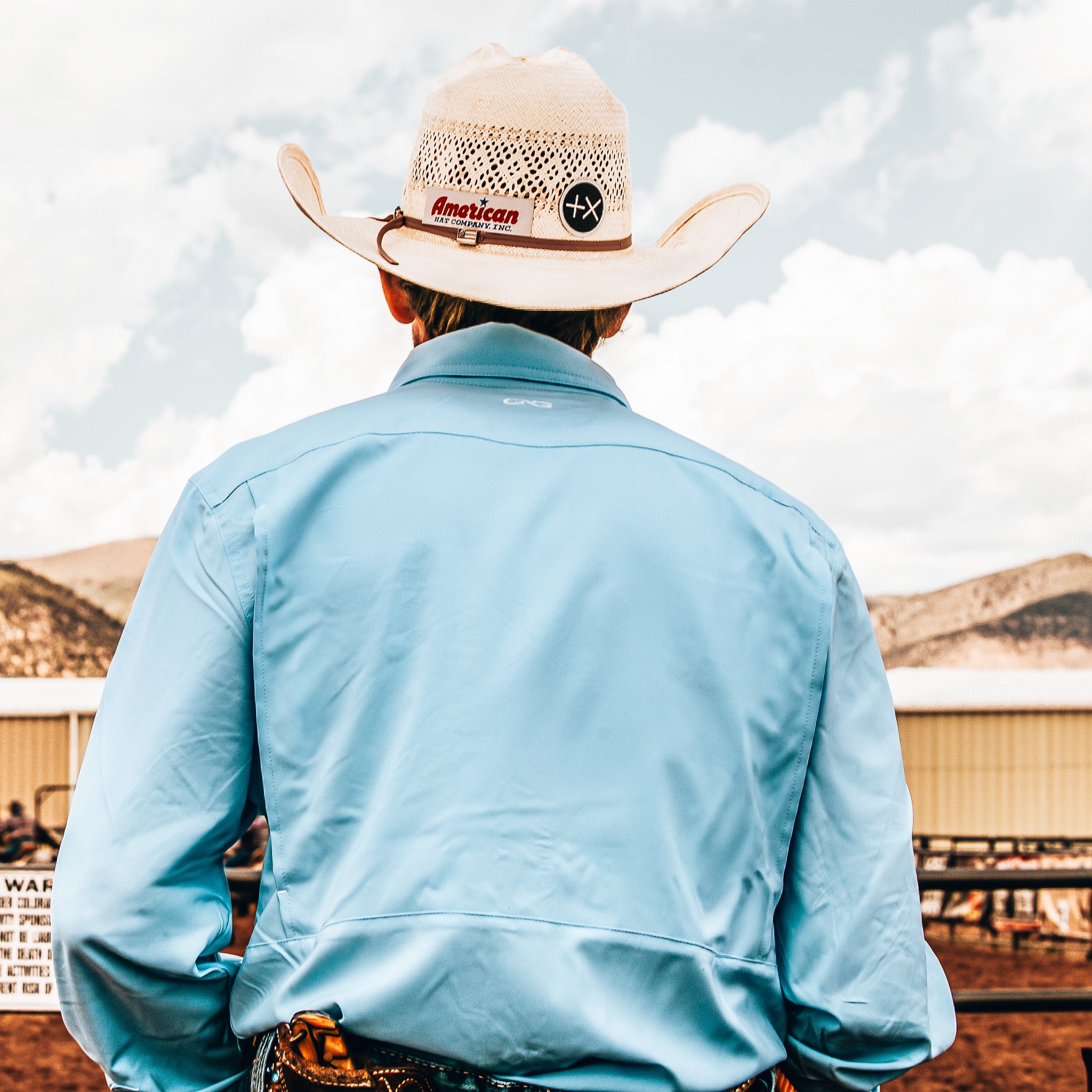 Person wearing a light blue jacket and cowboy hat with 'American' branding, standing in an outdoor setting.