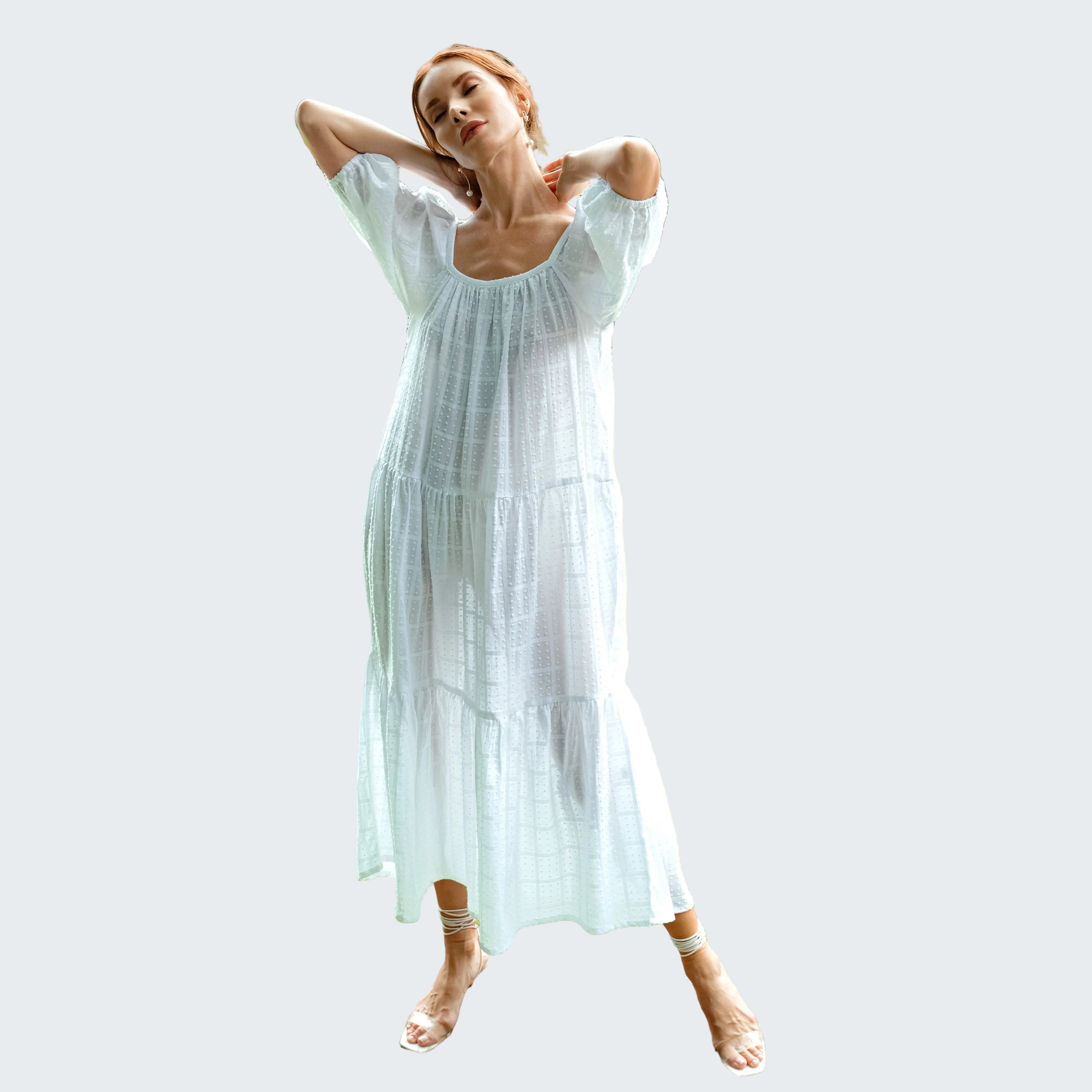 Woman in a white dress standing on grass with a blurred background