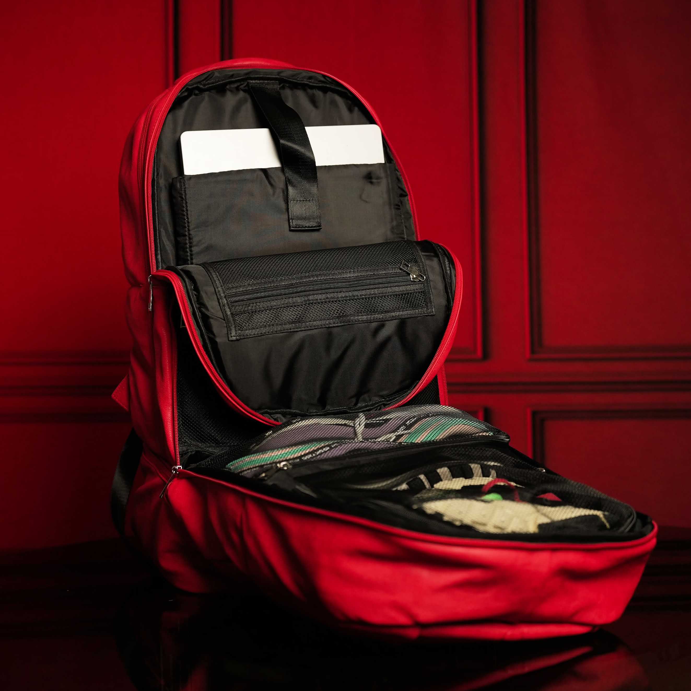 Red backpack with open compartment against a red wall