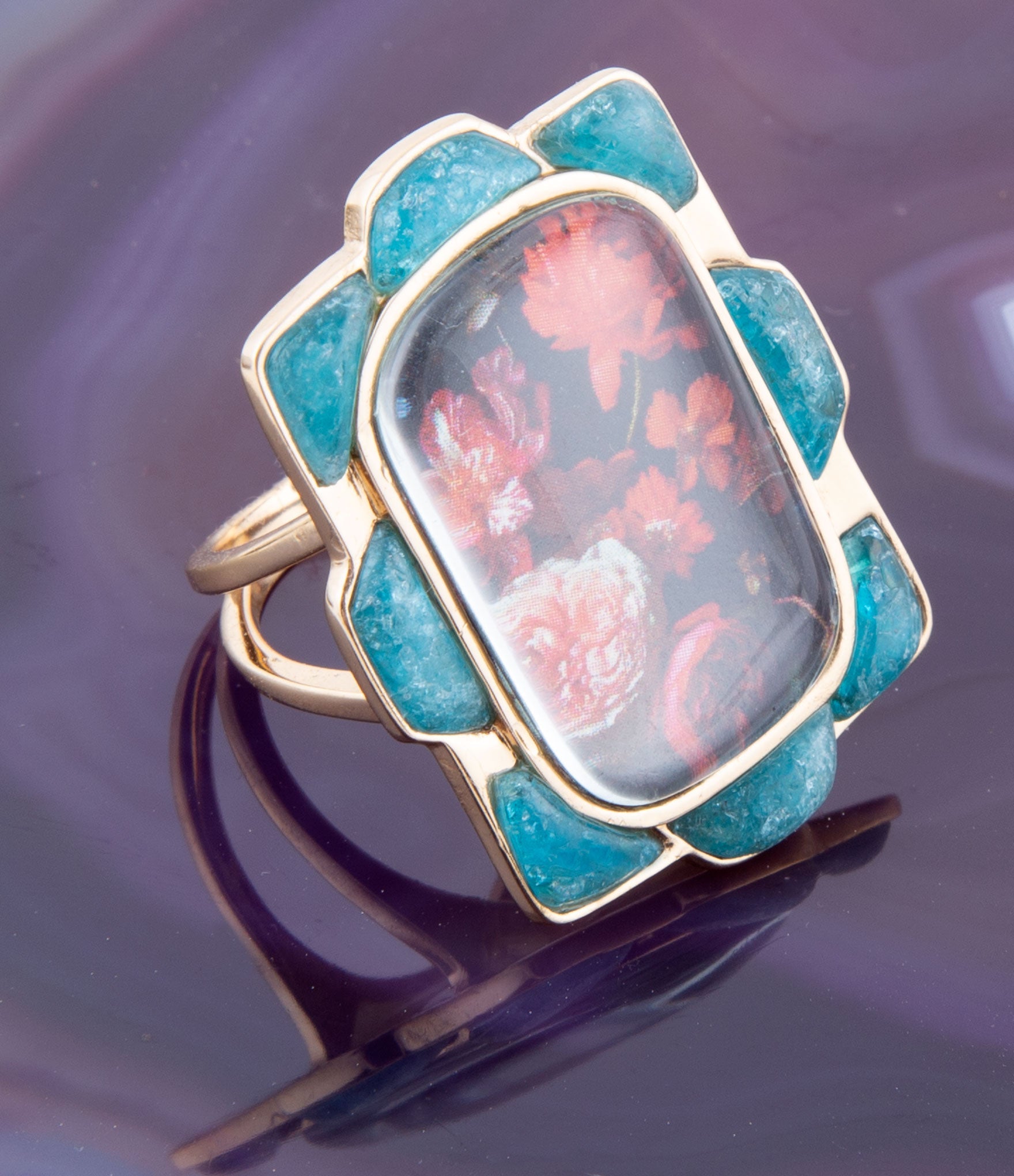 Ring with floral design and turquoise stones on a dark background