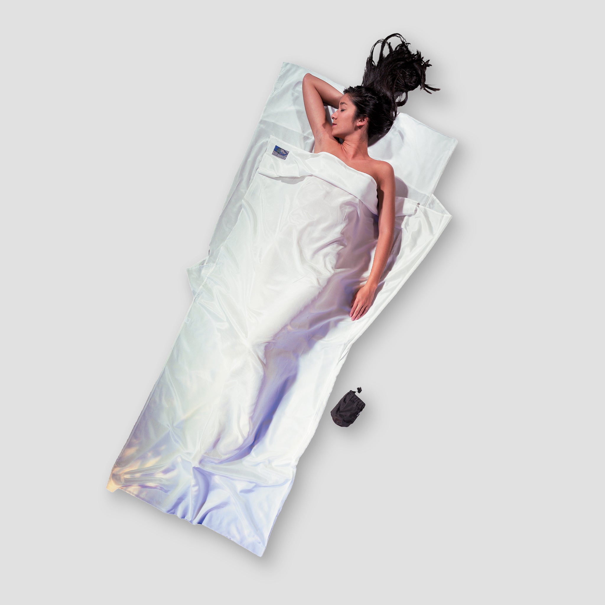 Person lying on a large white pillow with a gradient design against a light gray background