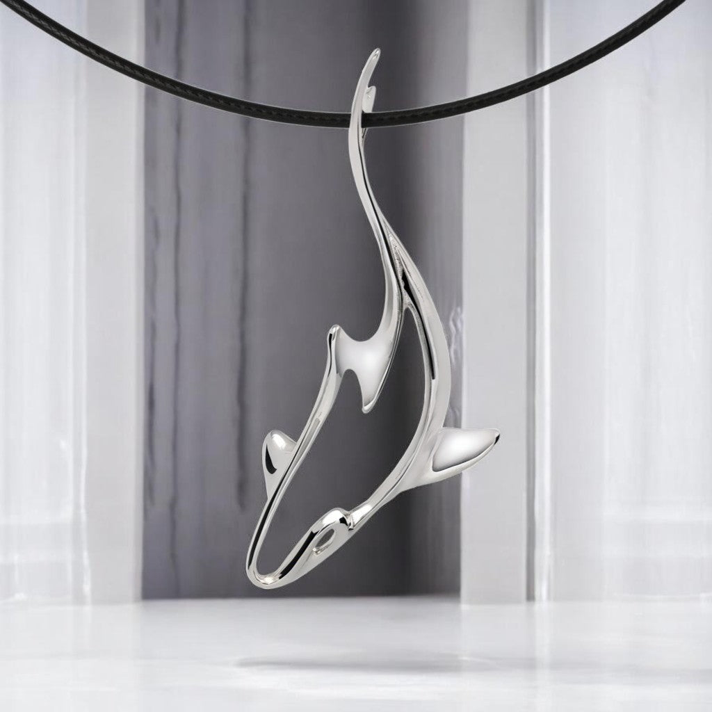 Silver shark pendant on a black cord against a gray and white striped background