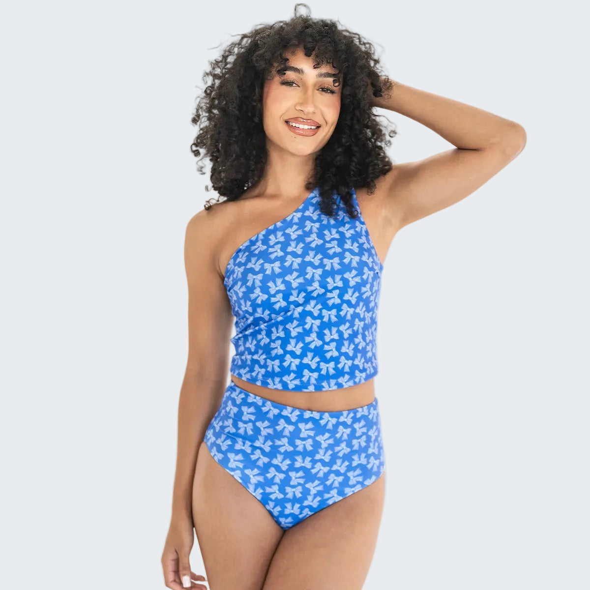 Woman wearing a blue floral one-shoulder bikini on a white background