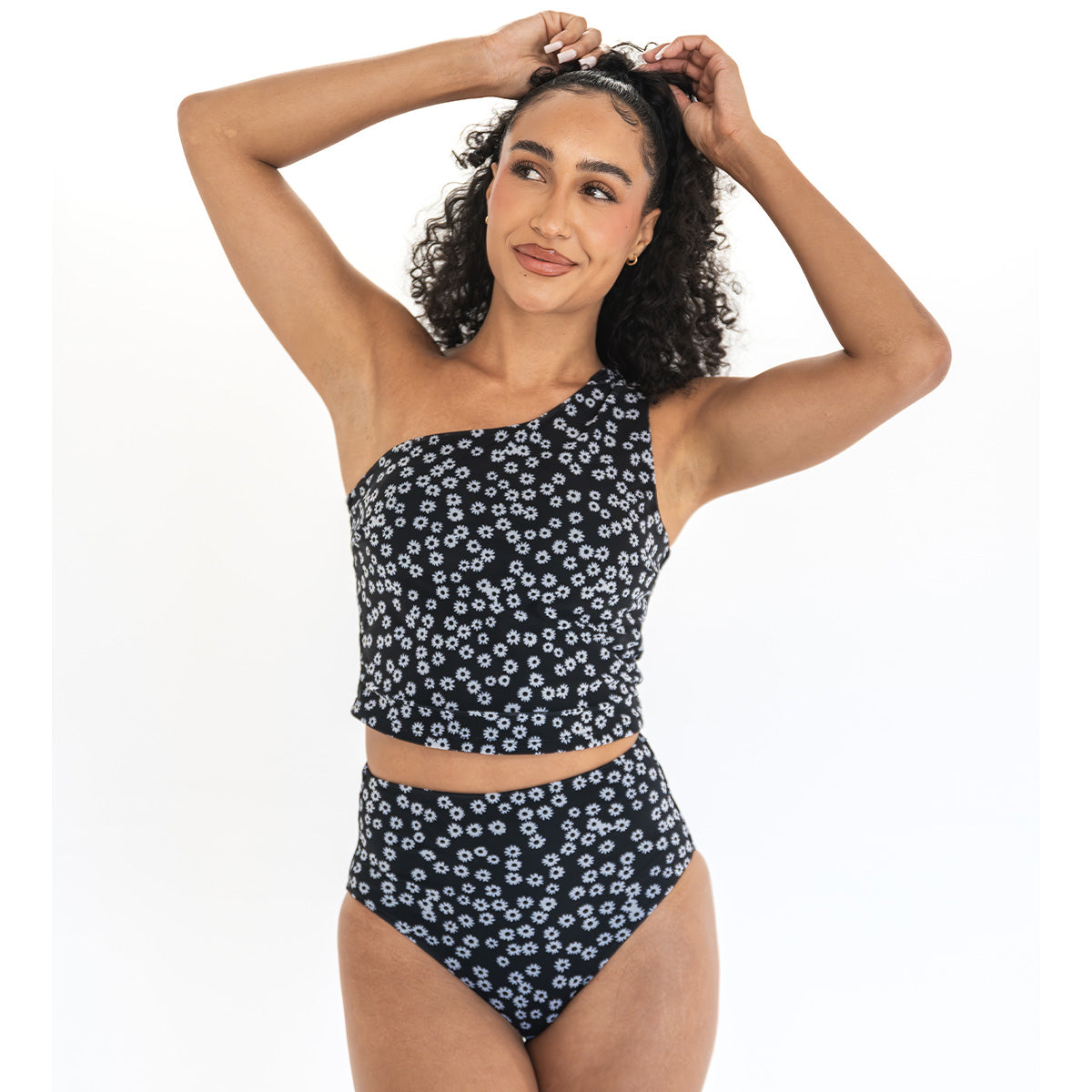 Woman wearing a navy floral one-shoulder swimsuit on a white background