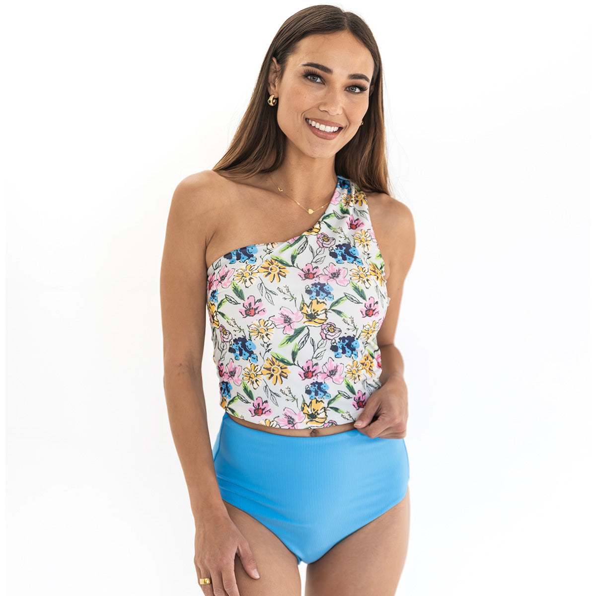 Woman wearing a floral one-shoulder top and blue high-waisted bikini bottom on a white background