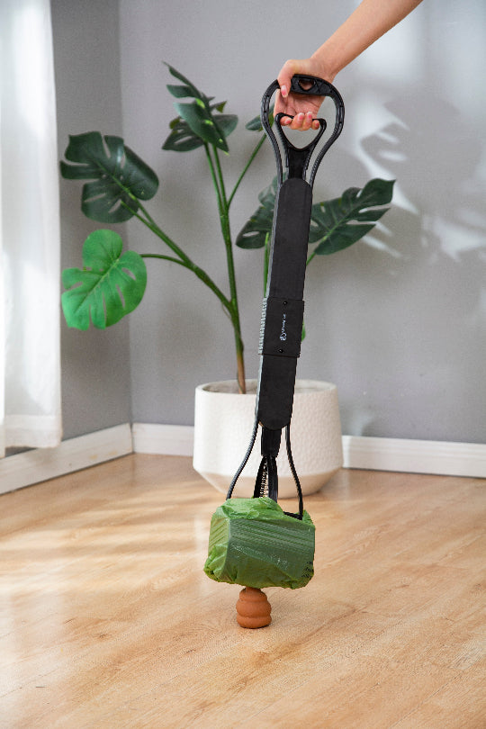 Person holding a plant with a green bag attached indoors.