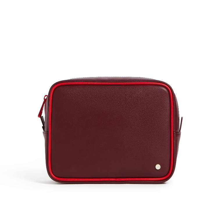A rectangular leather crossbody bag in deep burgundy with bright red piping and a small silver button detail, shown against a plain white background.