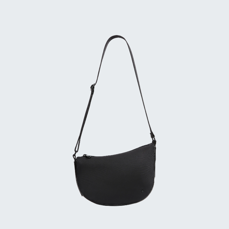 A black crescent-shaped shoulder bag with a slim adjustable strap, shown against a plain white background.