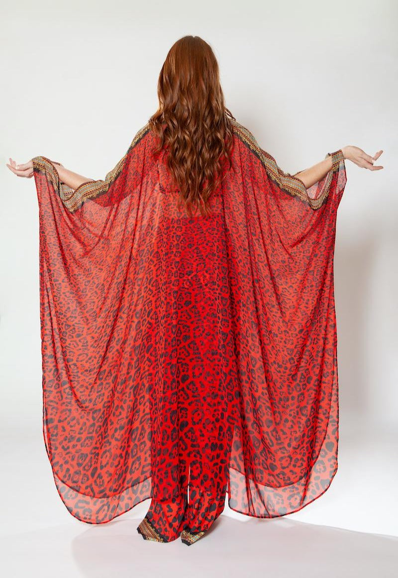 Person wearing a red patterned dress with arms outstretched on a white background
