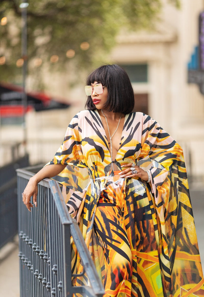 Woman wearing a colorful dress with abstract patterns leaning against a railing.