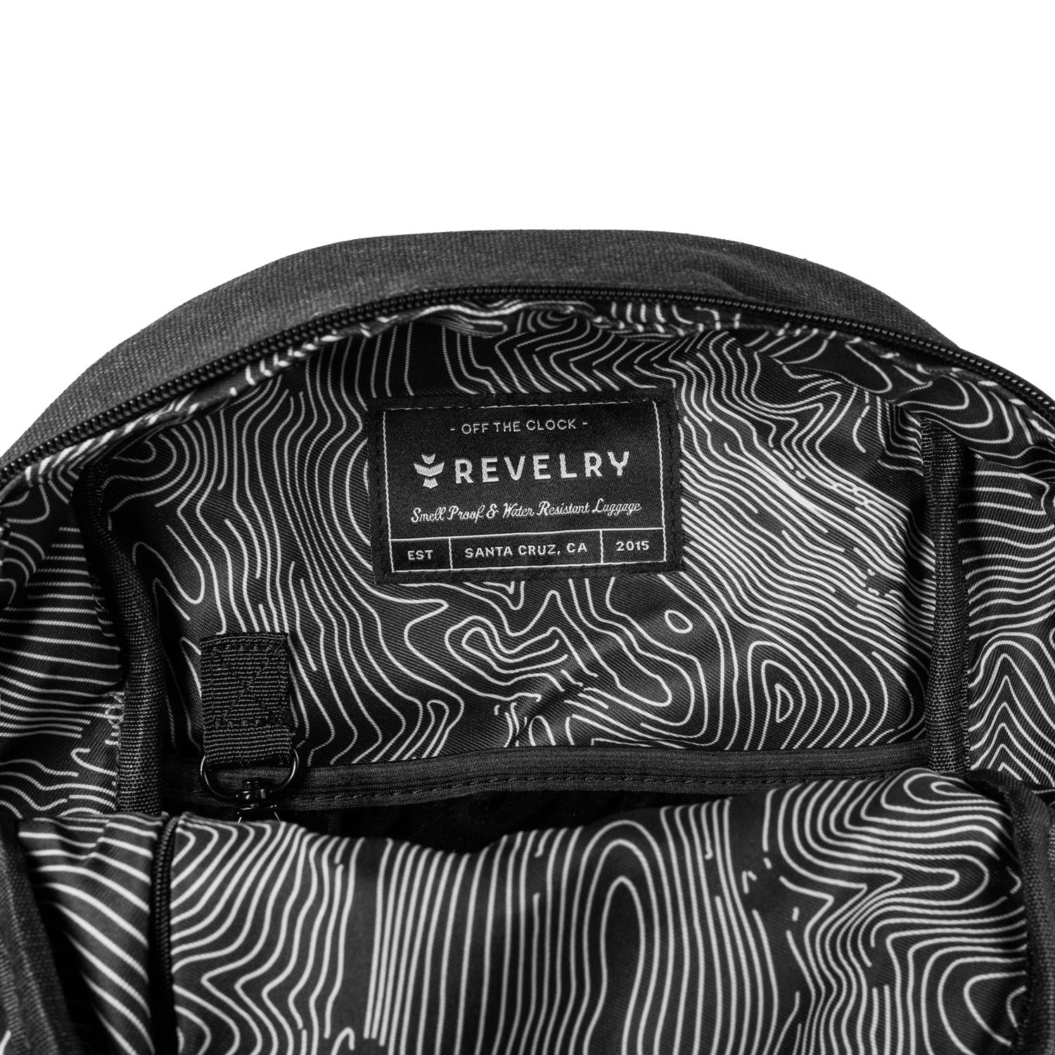 Close-up of a backpack with a patterned interior and Revelry brand label.