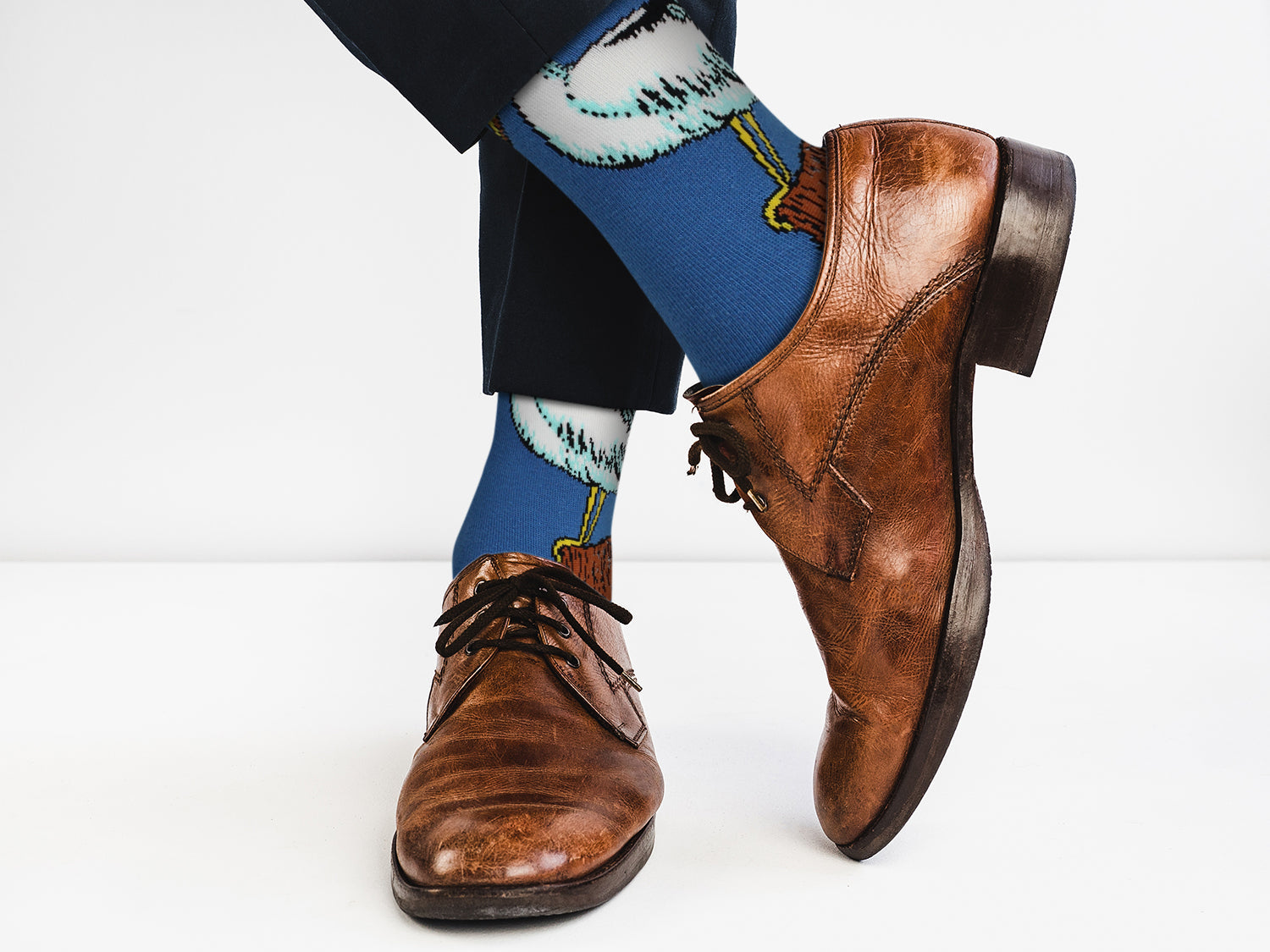 Brown dress shoes with blue socks featuring shark design on a white background
