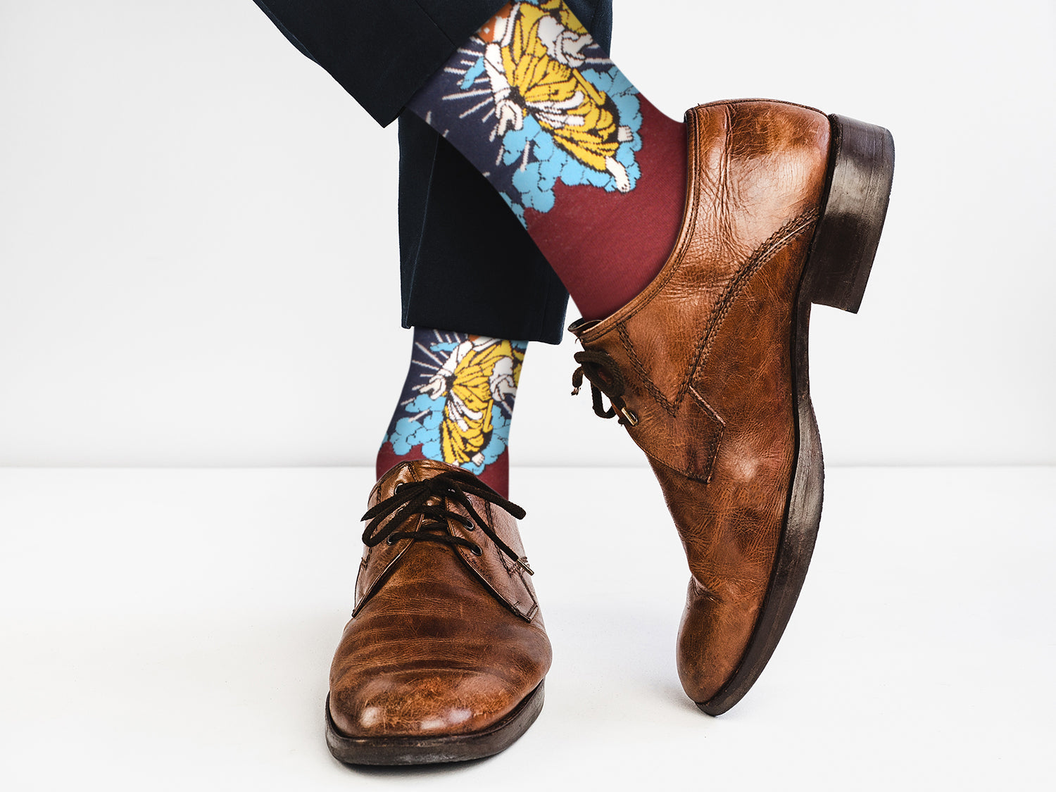 Brown dress shoes and colorful tiger-patterned socks on a white background