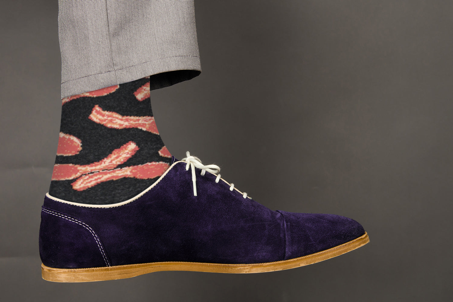 Purple suede shoe with a sock featuring bacon design on a gray background