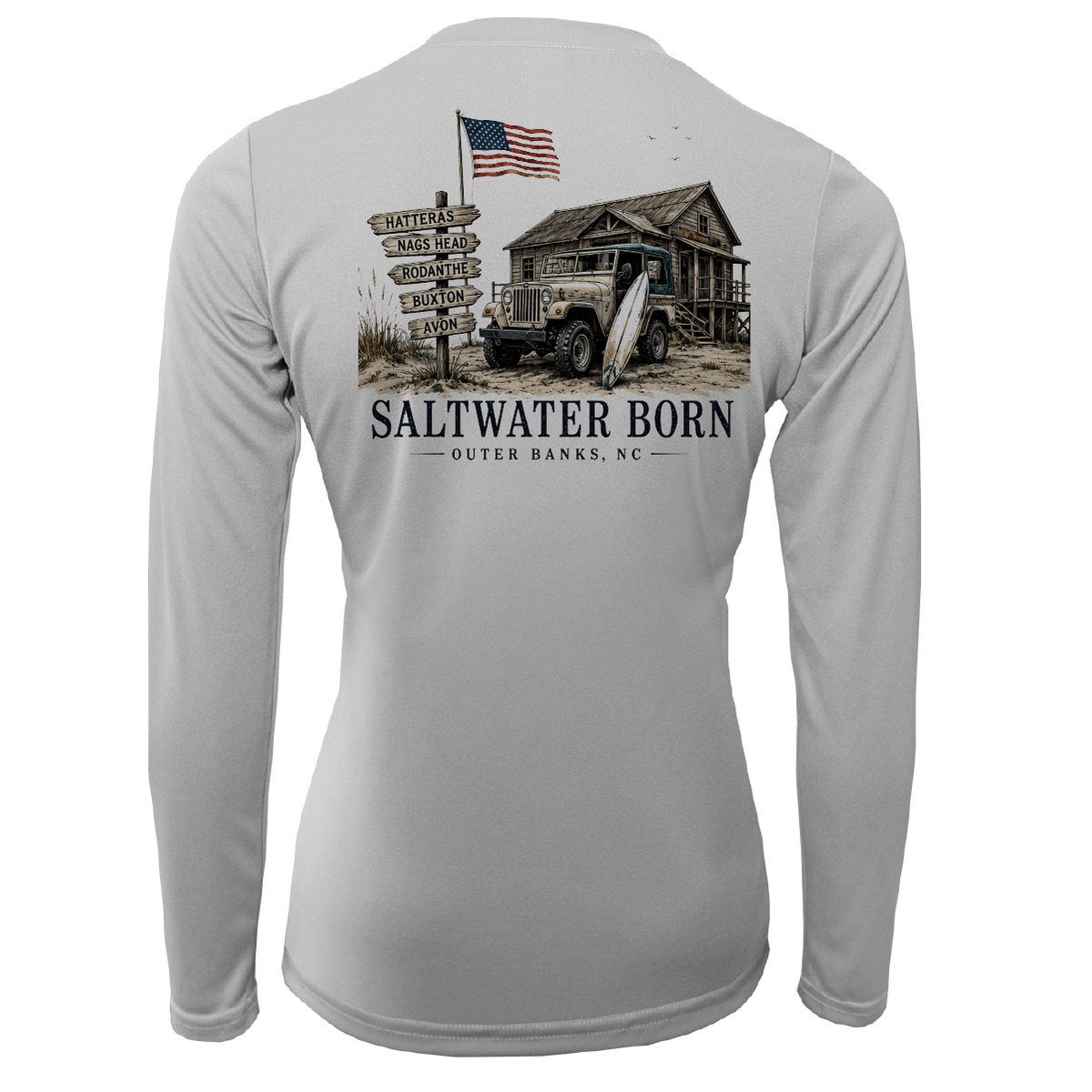 A light gray long-sleeve performance t-shirt shown from the back, featuring a large graphic print of a rustic cabin, vintage truck, signpost, and an American flag with the text 'SALTWATER BORN OUTER BANKS, NC'.
