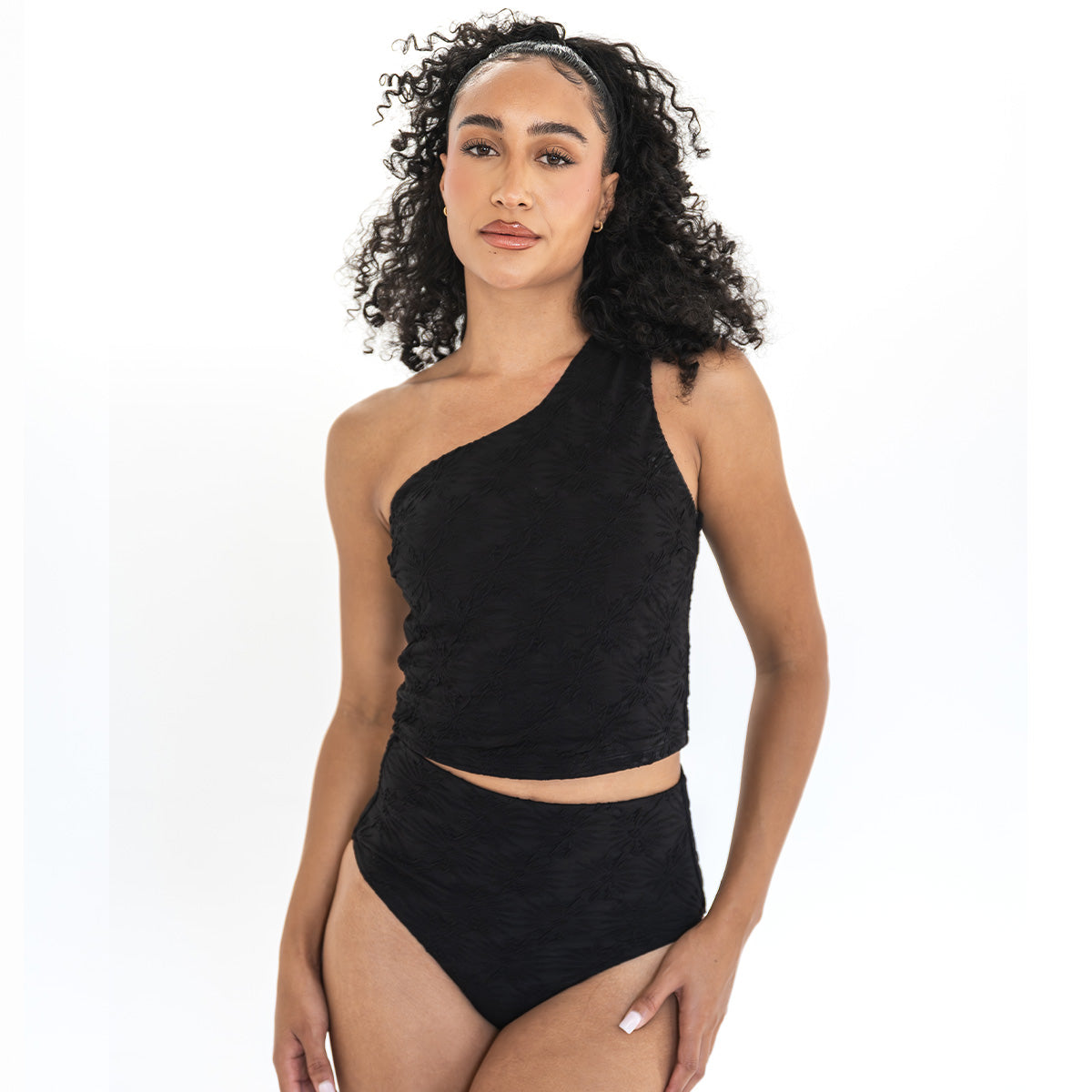 Woman wearing a black one-shoulder top and high-waisted bikini bottom on a white background