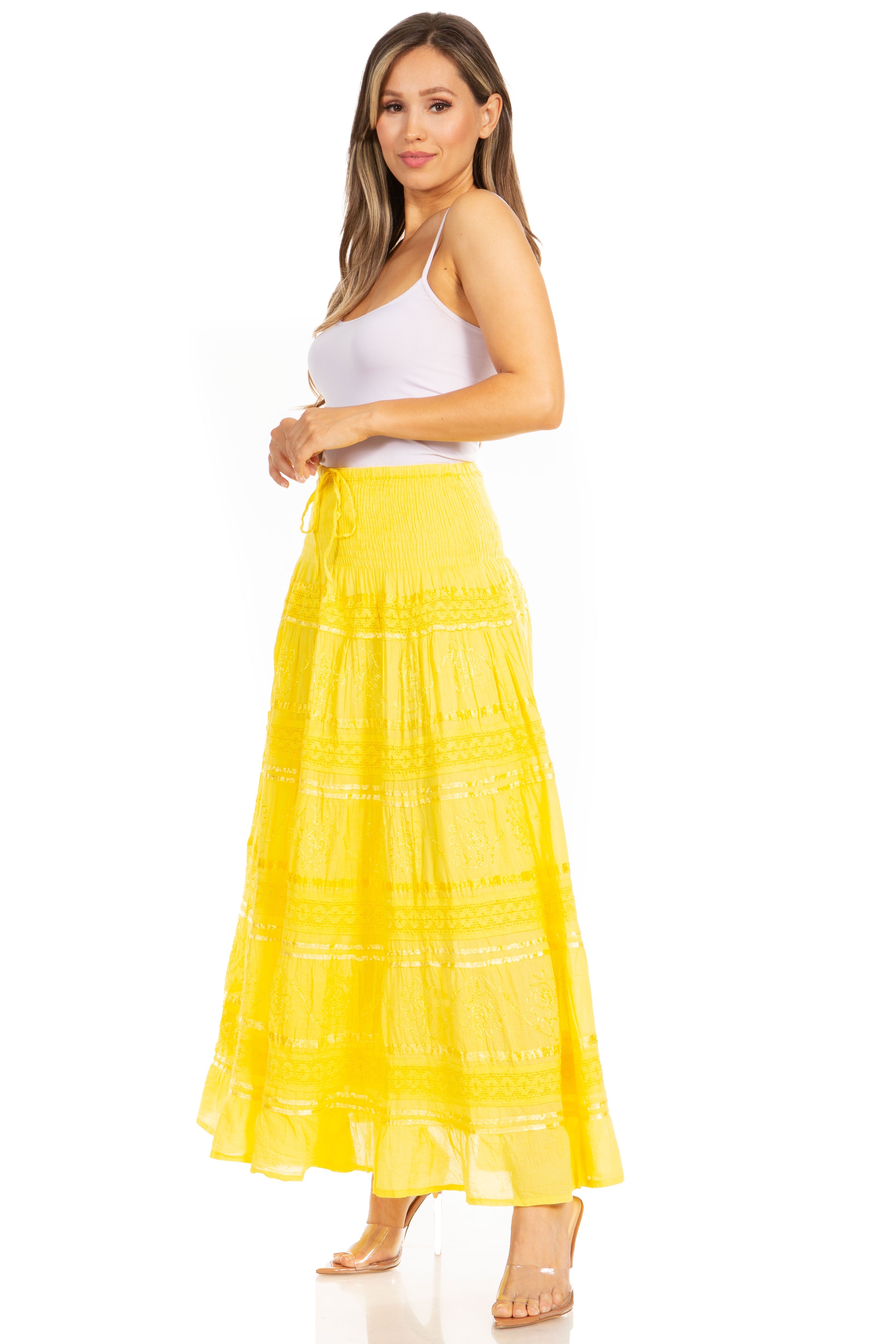 Woman wearing a yellow tiered skirt and white top on a white background