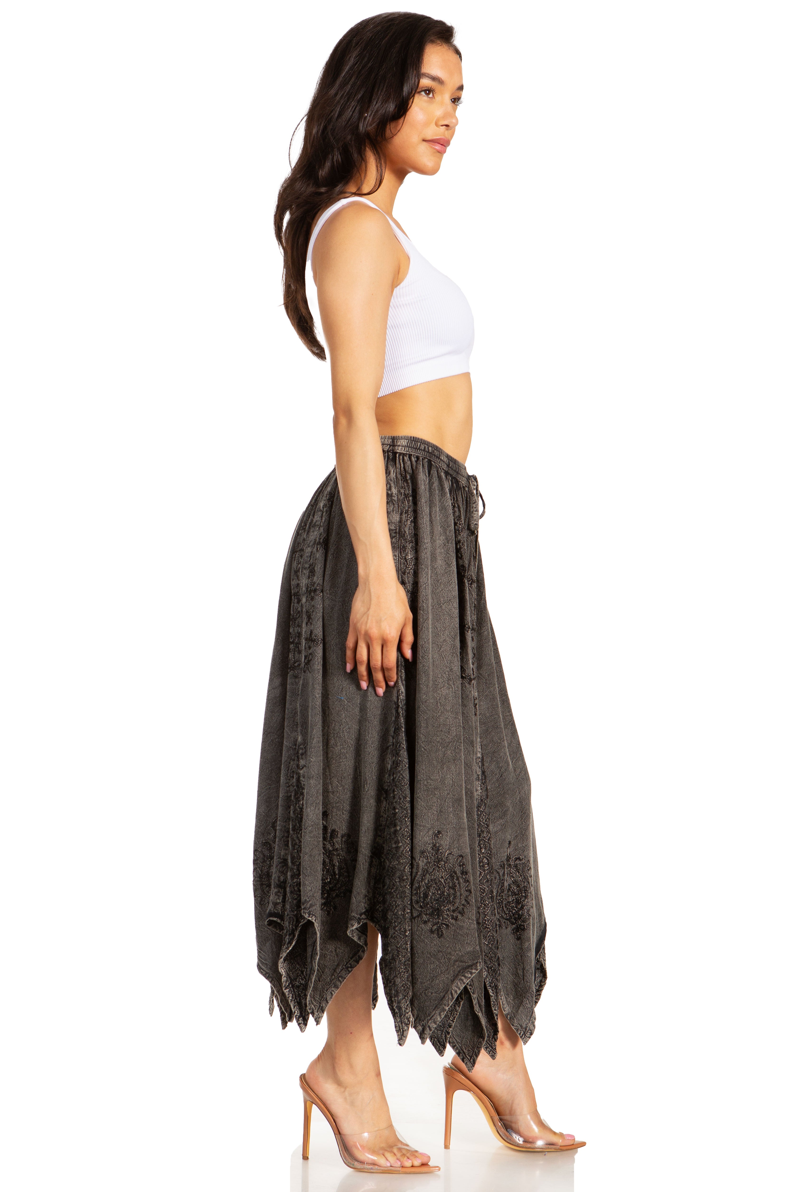 Woman wearing a white top and dark gray flowing pants on a white background