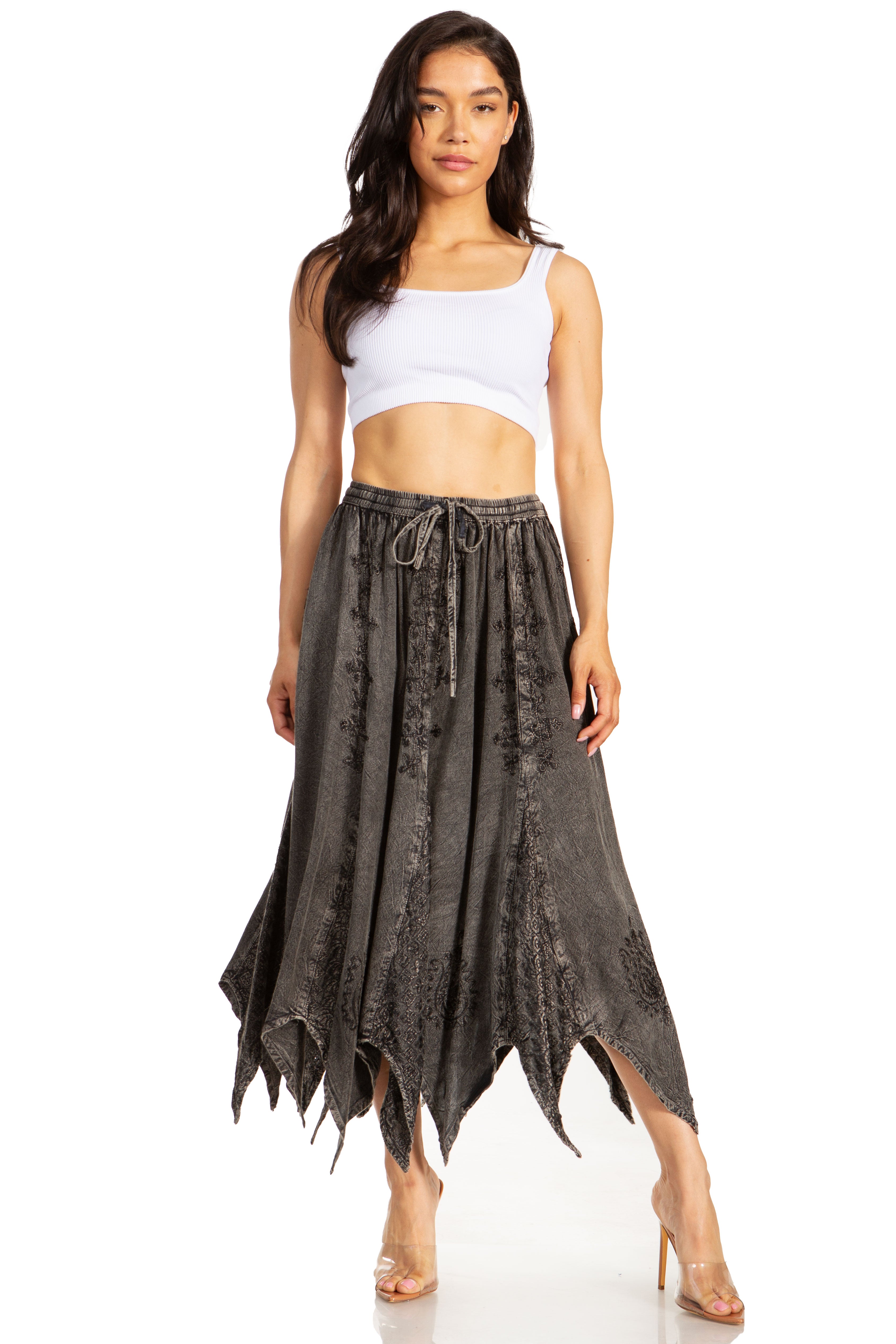 Woman wearing a white crop top and dark patterned skirt on a white background