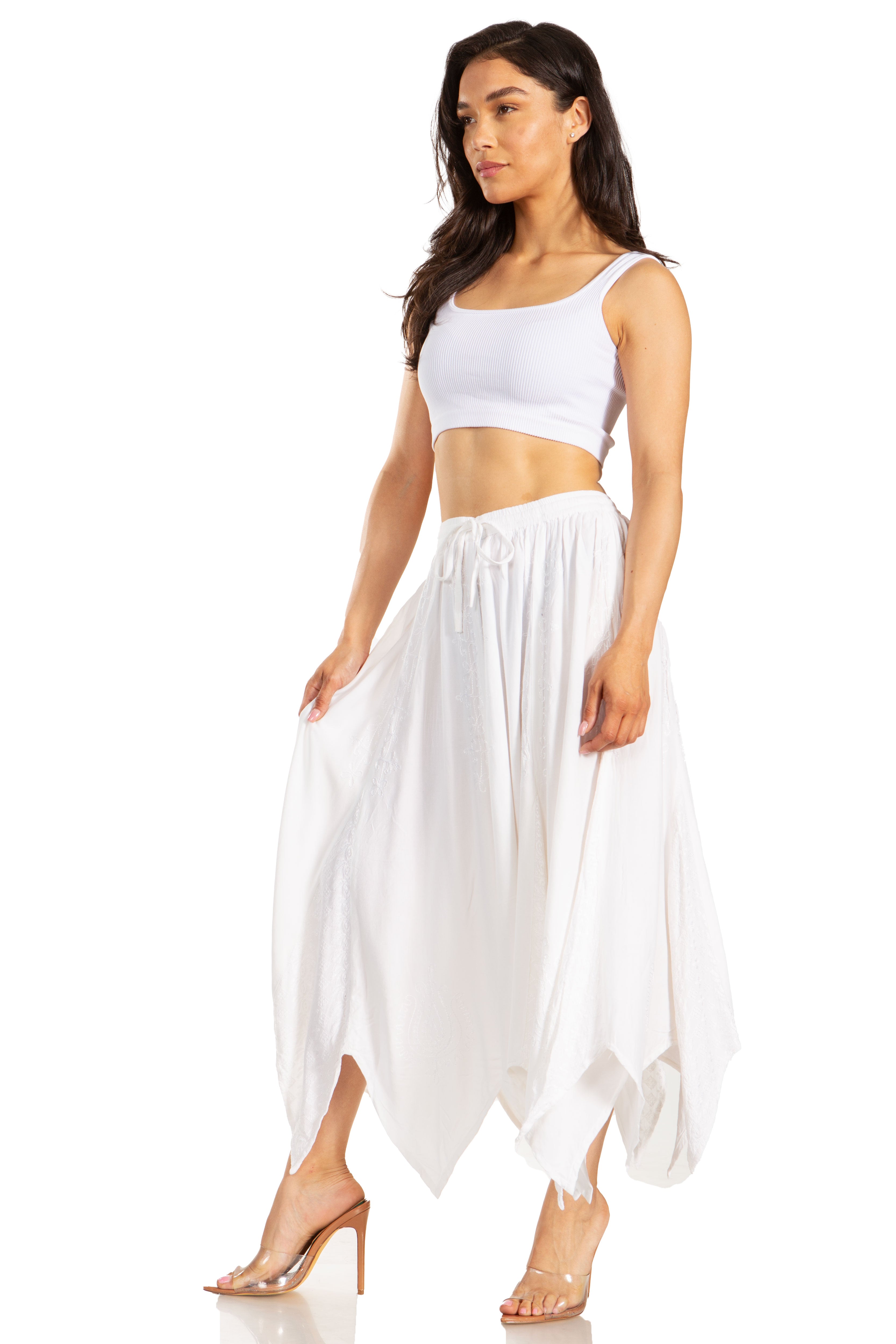 Woman wearing a white sleeveless top and flowing white skirt on a white background