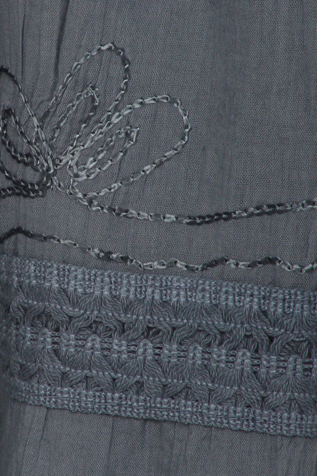 Close-up of a gray fabric with floral embroidery and lace details.