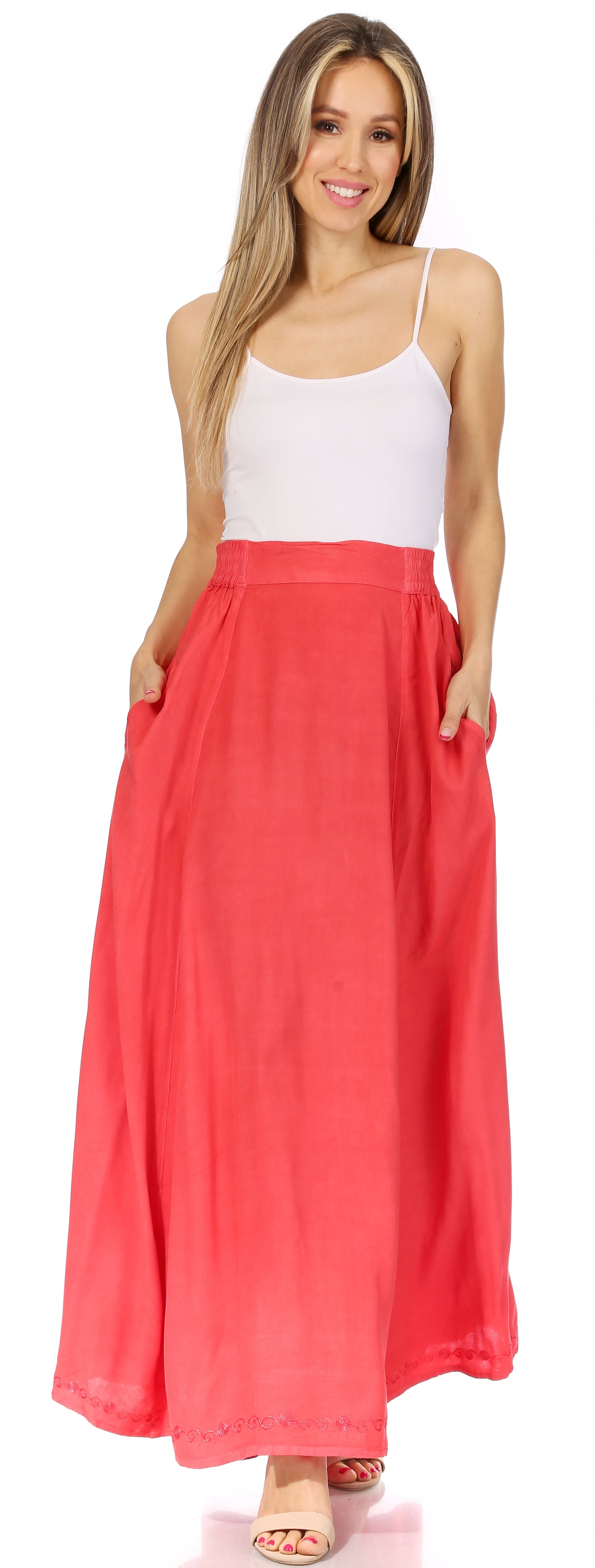 Woman wearing a white top and coral maxi skirt on a white background