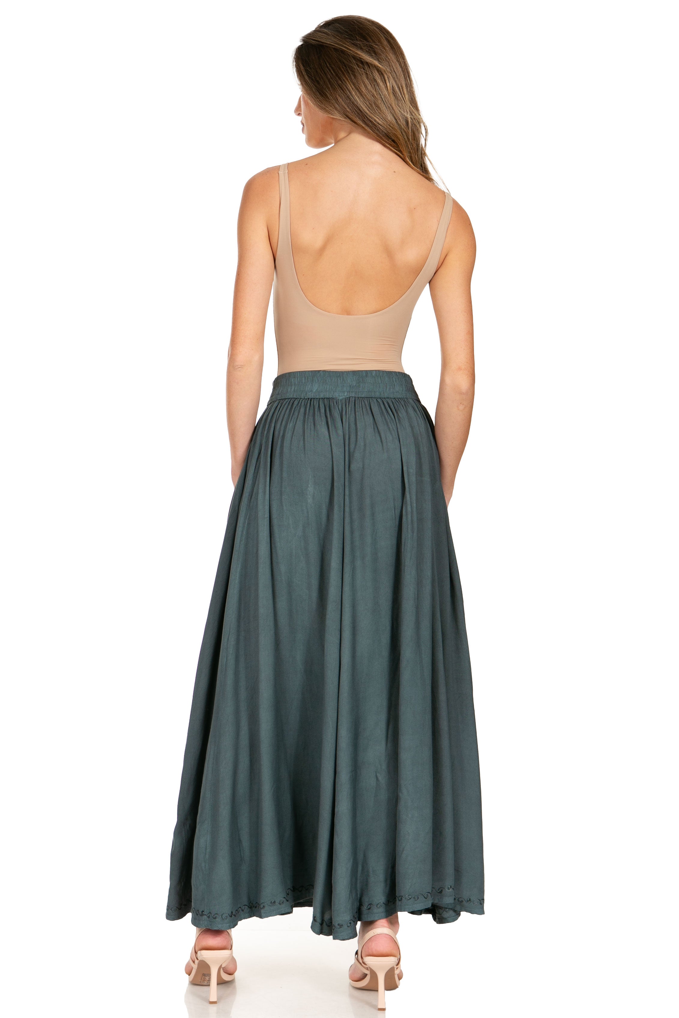 Woman wearing a long teal skirt with a white background