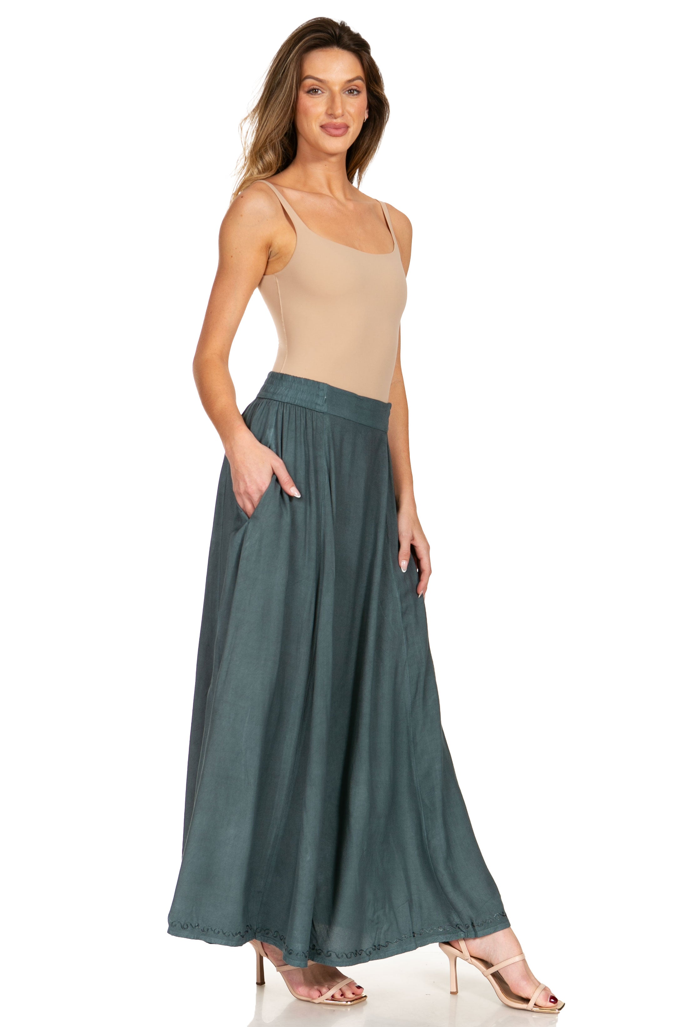 Woman wearing a beige top and teal skirt on a white background