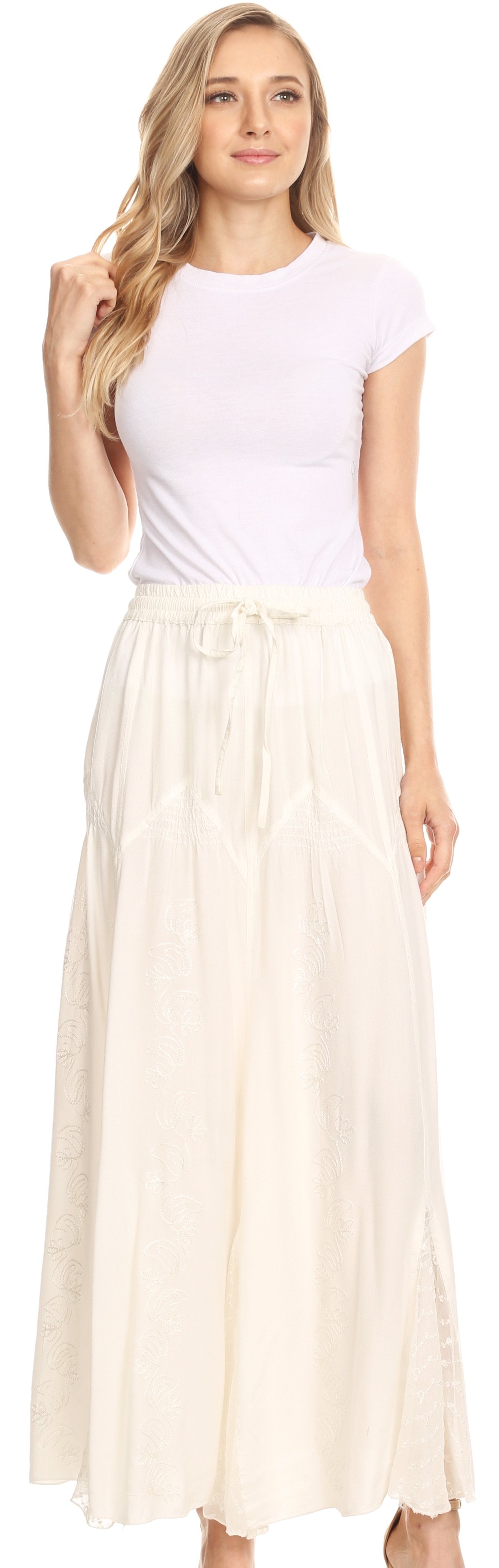 Woman wearing a white top and beige skirt against a neutral background