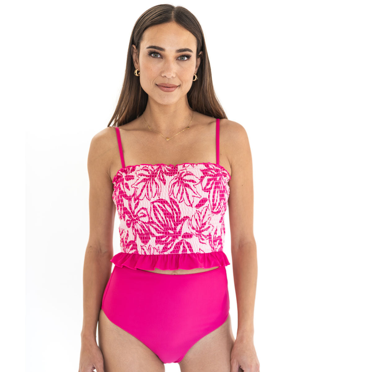Woman wearing a pink and white floral bikini with ruffled details on a white background