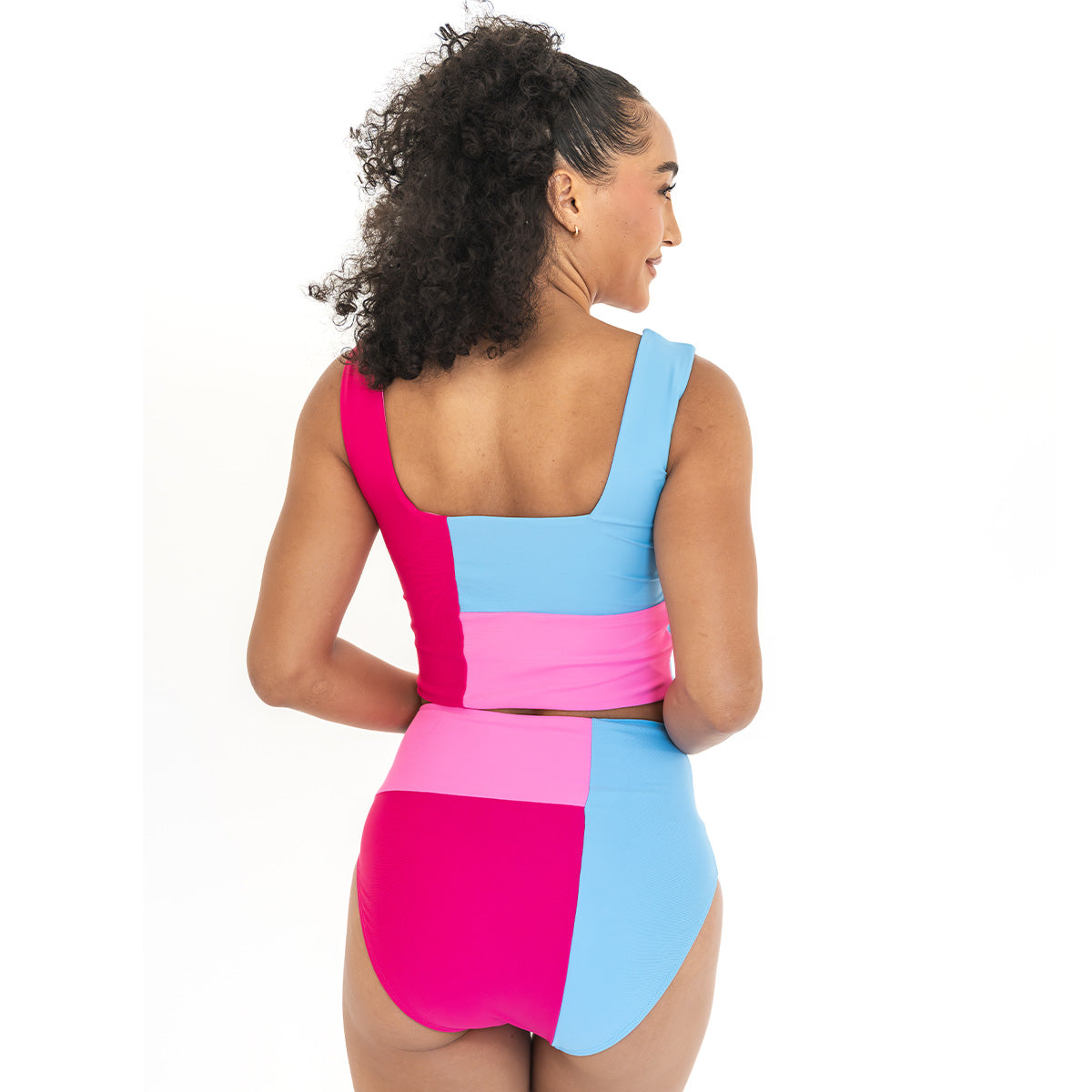 Woman wearing a colorful swimsuit with pink and blue design on a white background