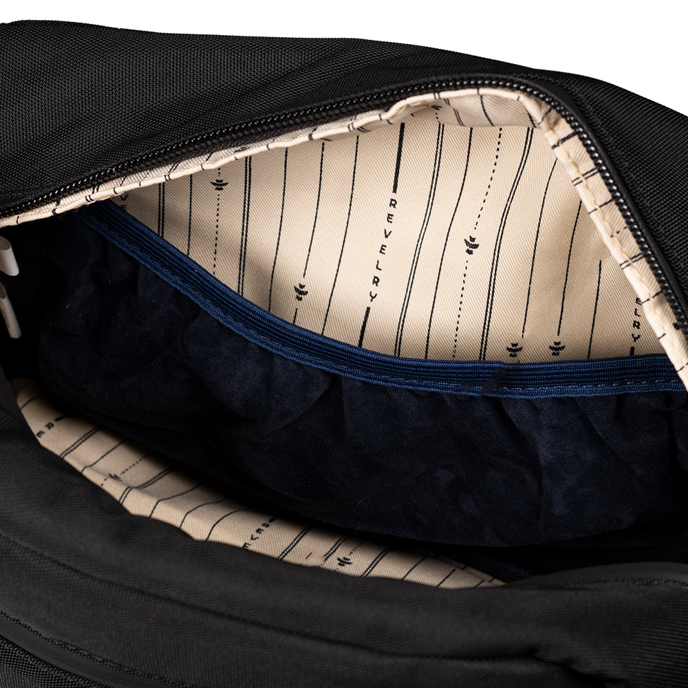 Close-up of a black bag with a striped interior lining, featuring the brand 'Revelry'.