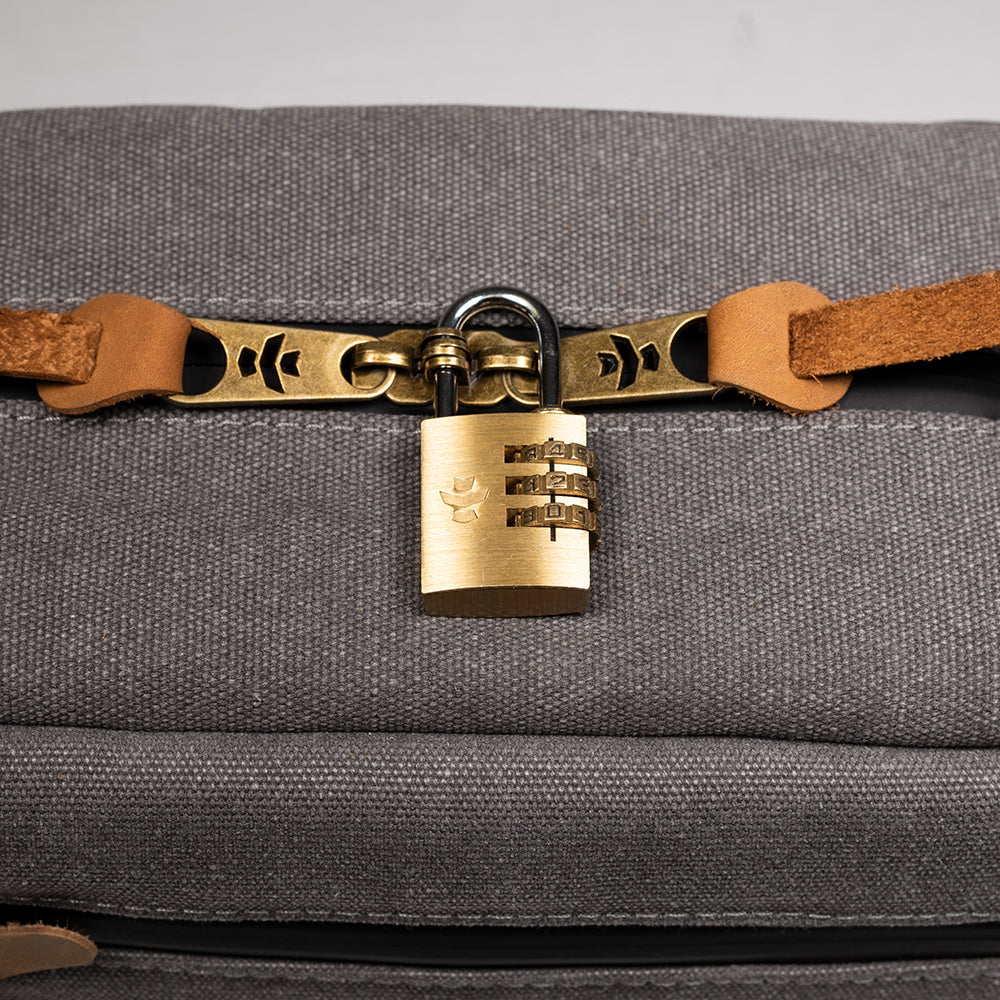 Gray bag with a gold lock and brown strap on a gray background