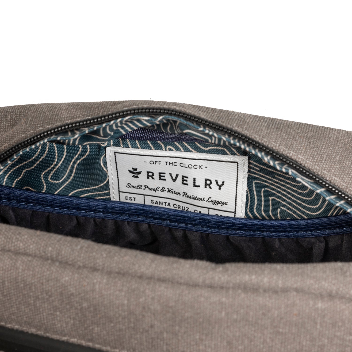 Close-up of a gray bag with a patterned interior and 'Revelry' label.