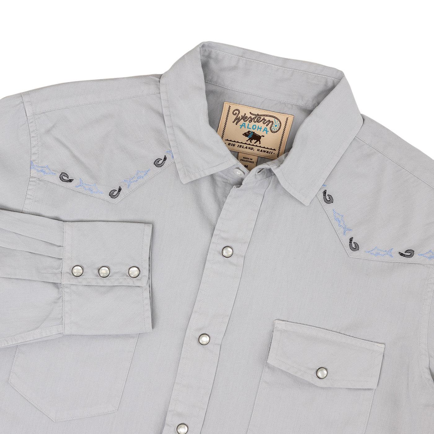 Gray shirt with embroidery details and a brand label on a white background