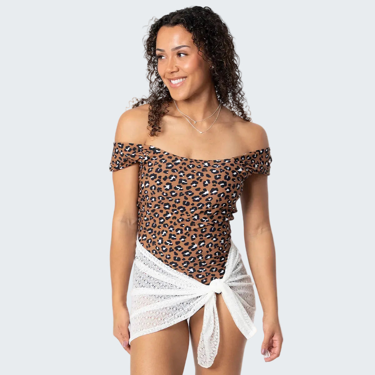 Woman wearing a leopard print off-shoulder top with a white skirt on a white background