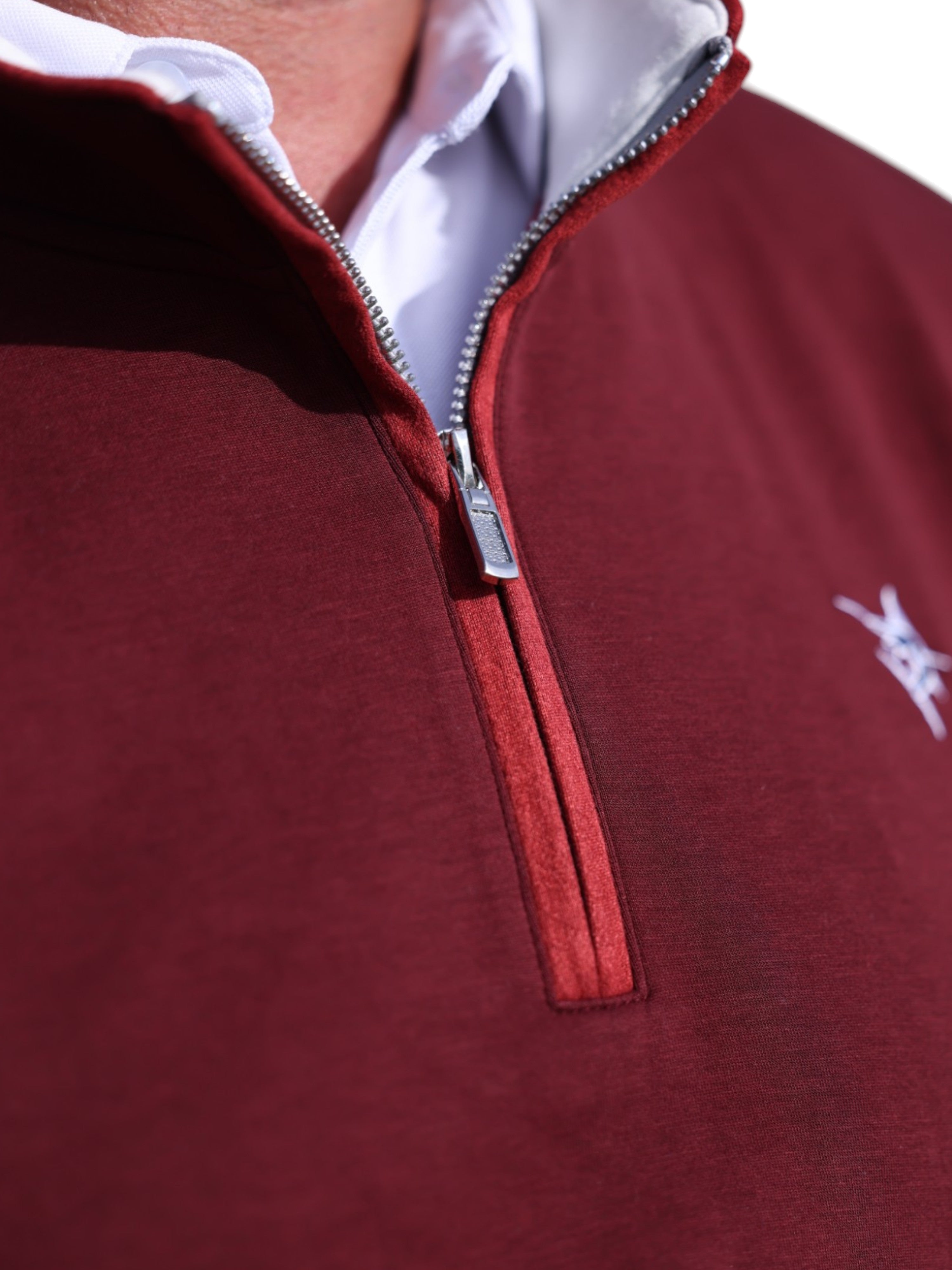 Close-up of a red quarter-zip sweatshirt with a brand logo on a white background