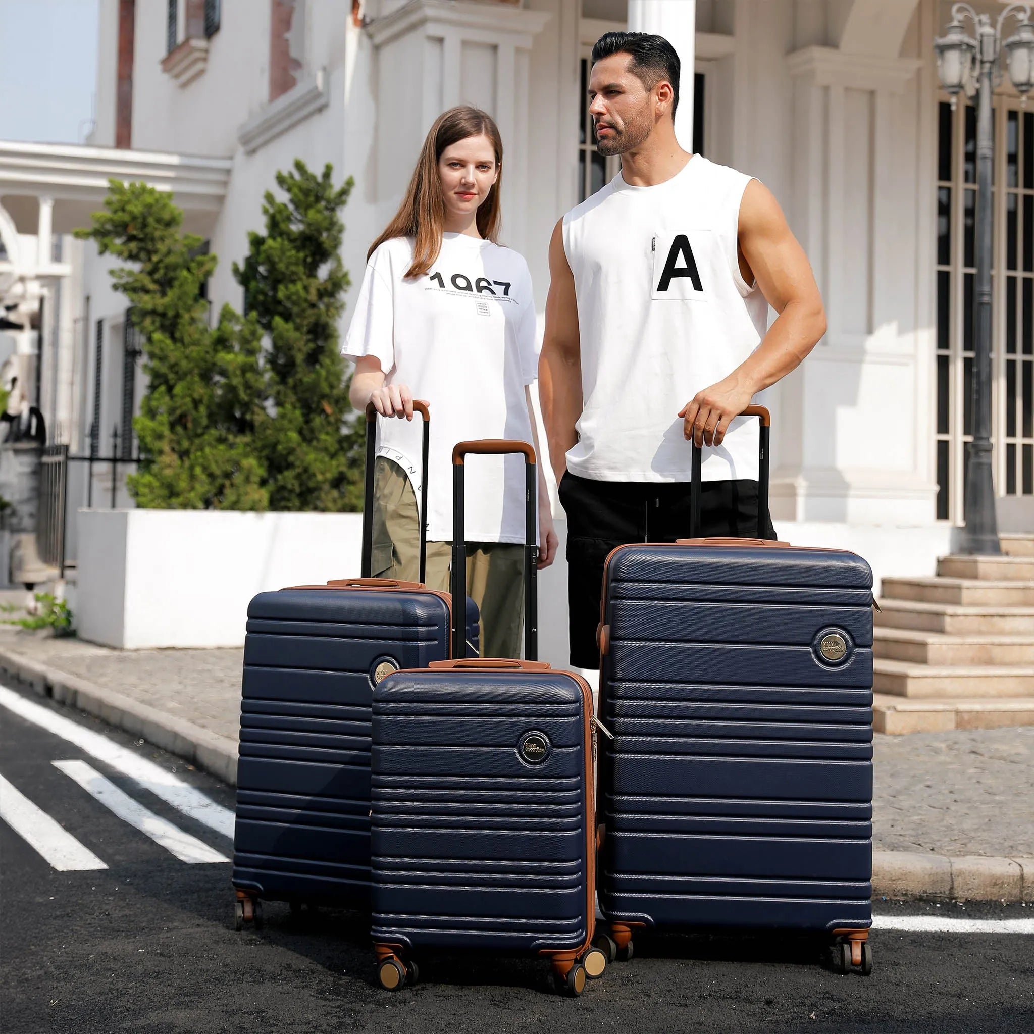 Two people with navy blue suitcases on a street.