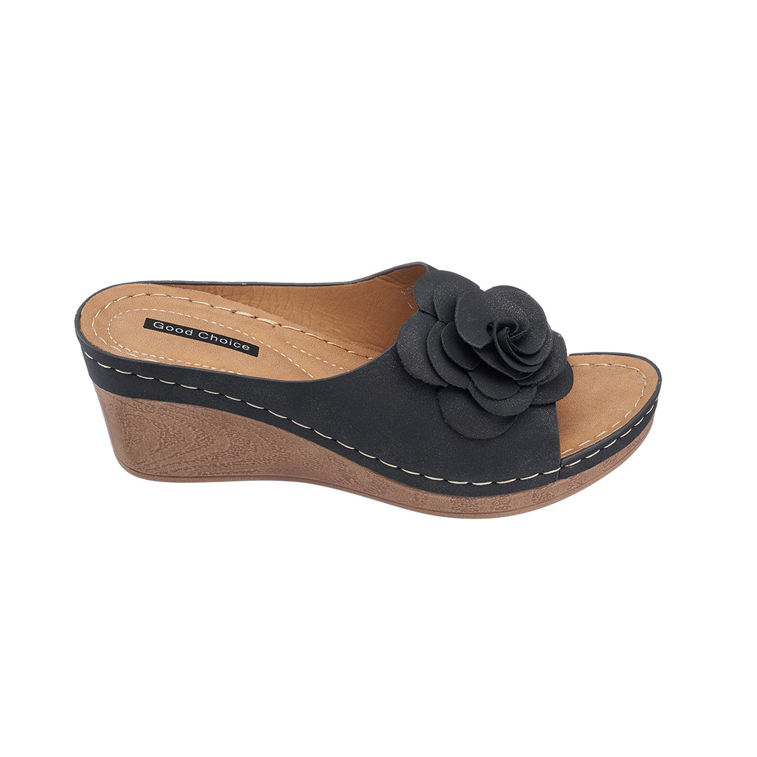 Black wedge sandal with a flower detail on a white background