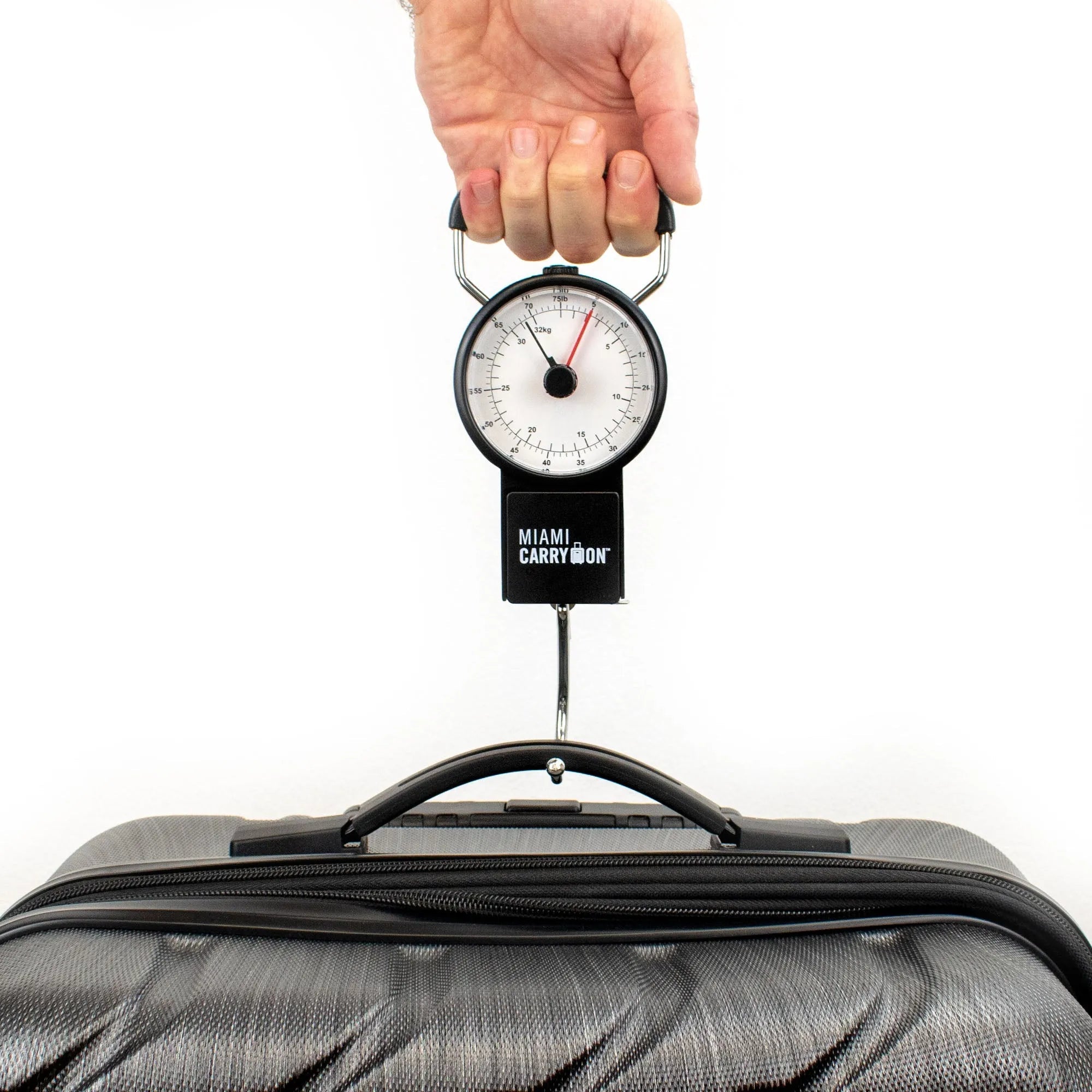 Hand using a dial gauge to measure weight on a suitcase with 'Miami Carry-On' branding.