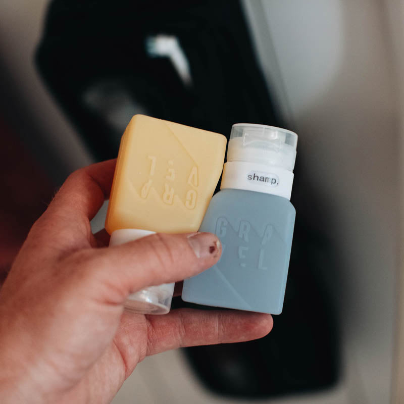 Hand holding a bar of soap and a small bottle with 'GRUEL' branding.